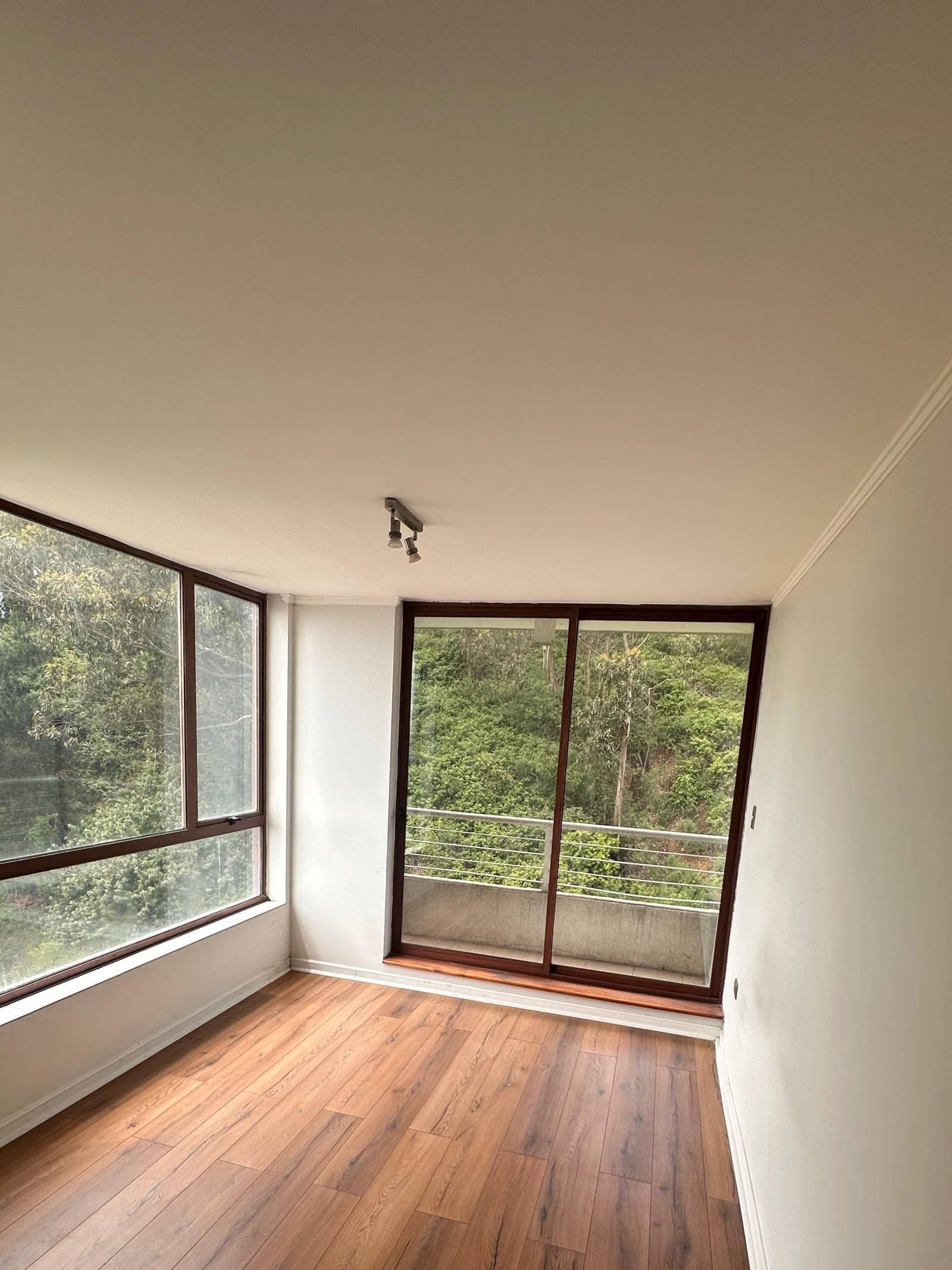 Habitación vacía con piso de madera y balcón.