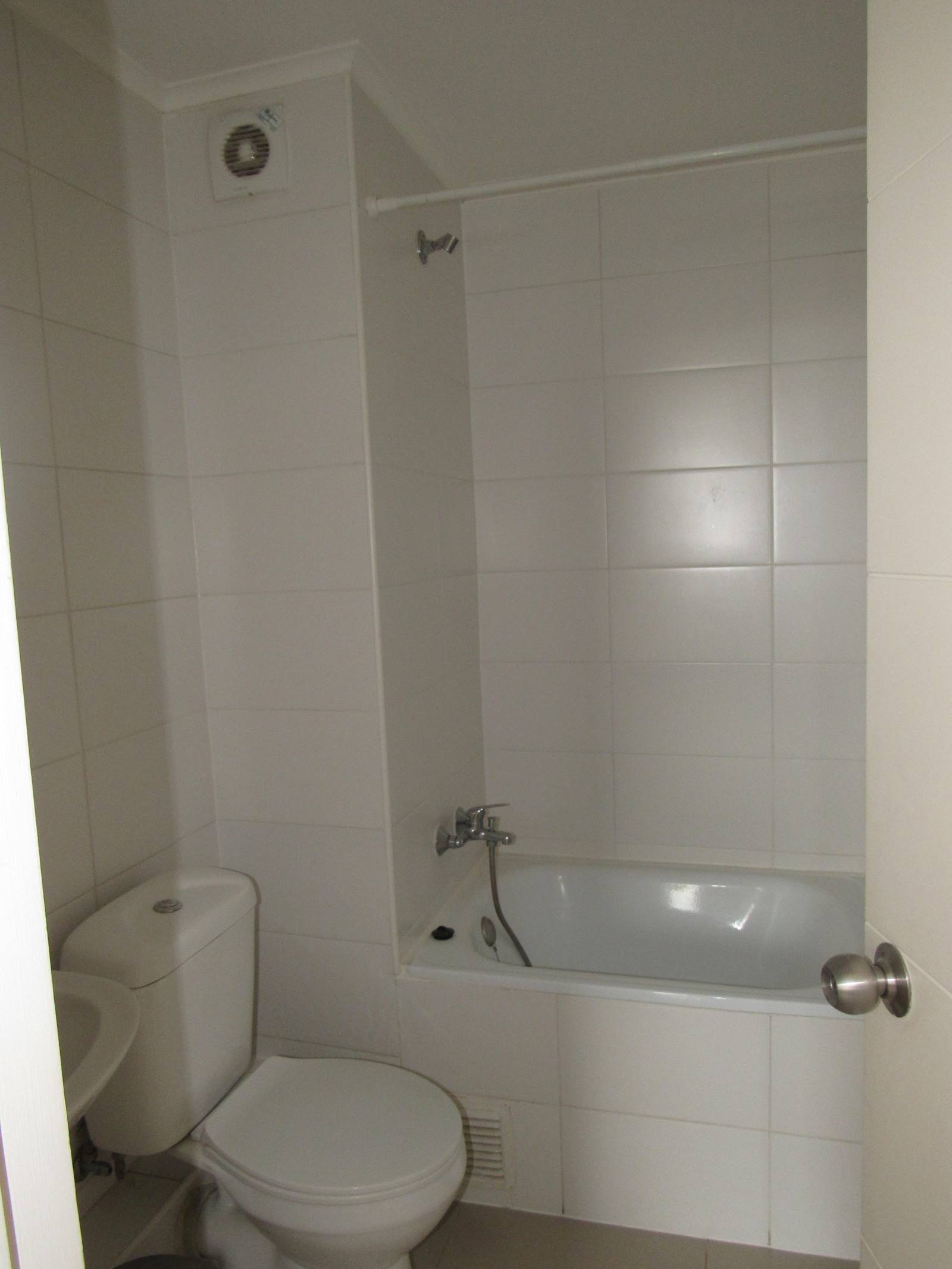Baño con tina, inodoro y paredes completamente revestidas en azulejos.