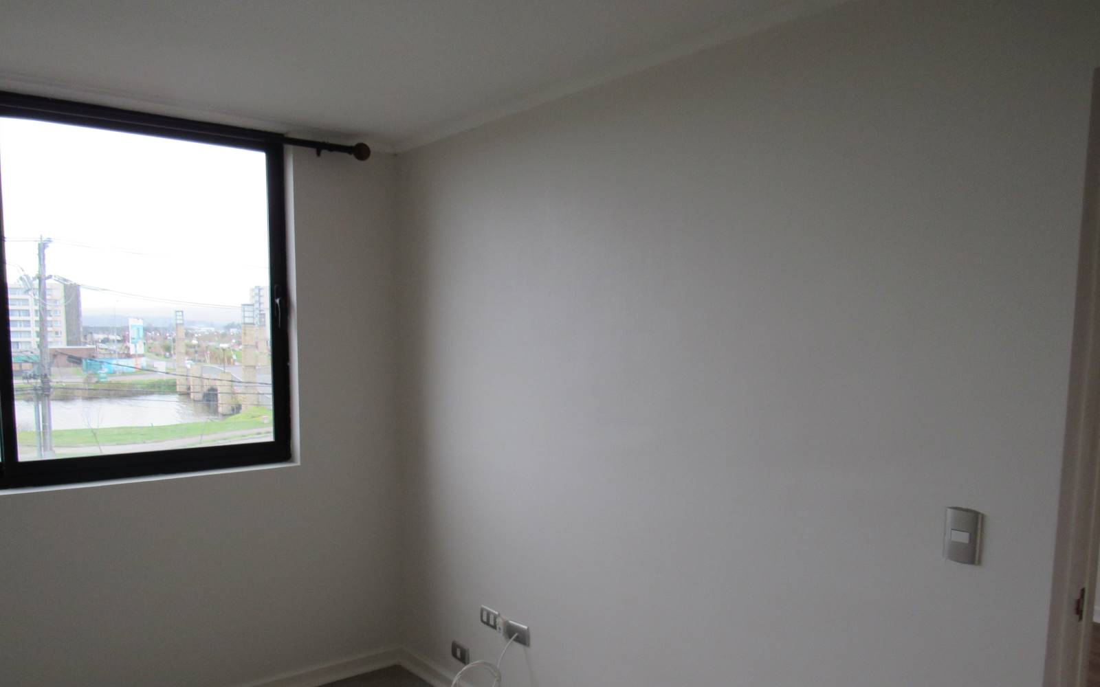 Pared de dormitorio junto a ventana con vista urbana.
