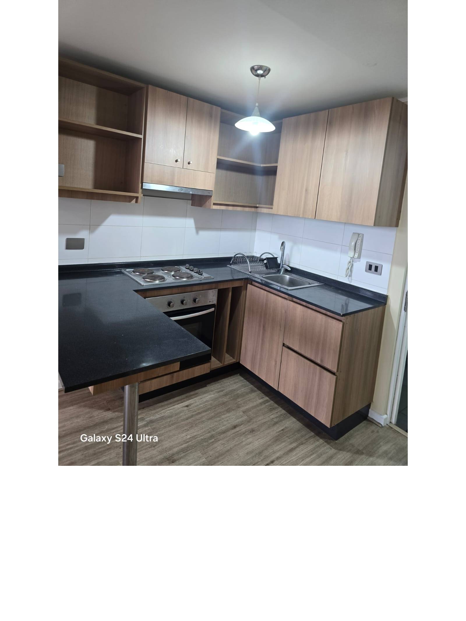 Cocina equipada con encimera, horno empotrado y muebles de madera.