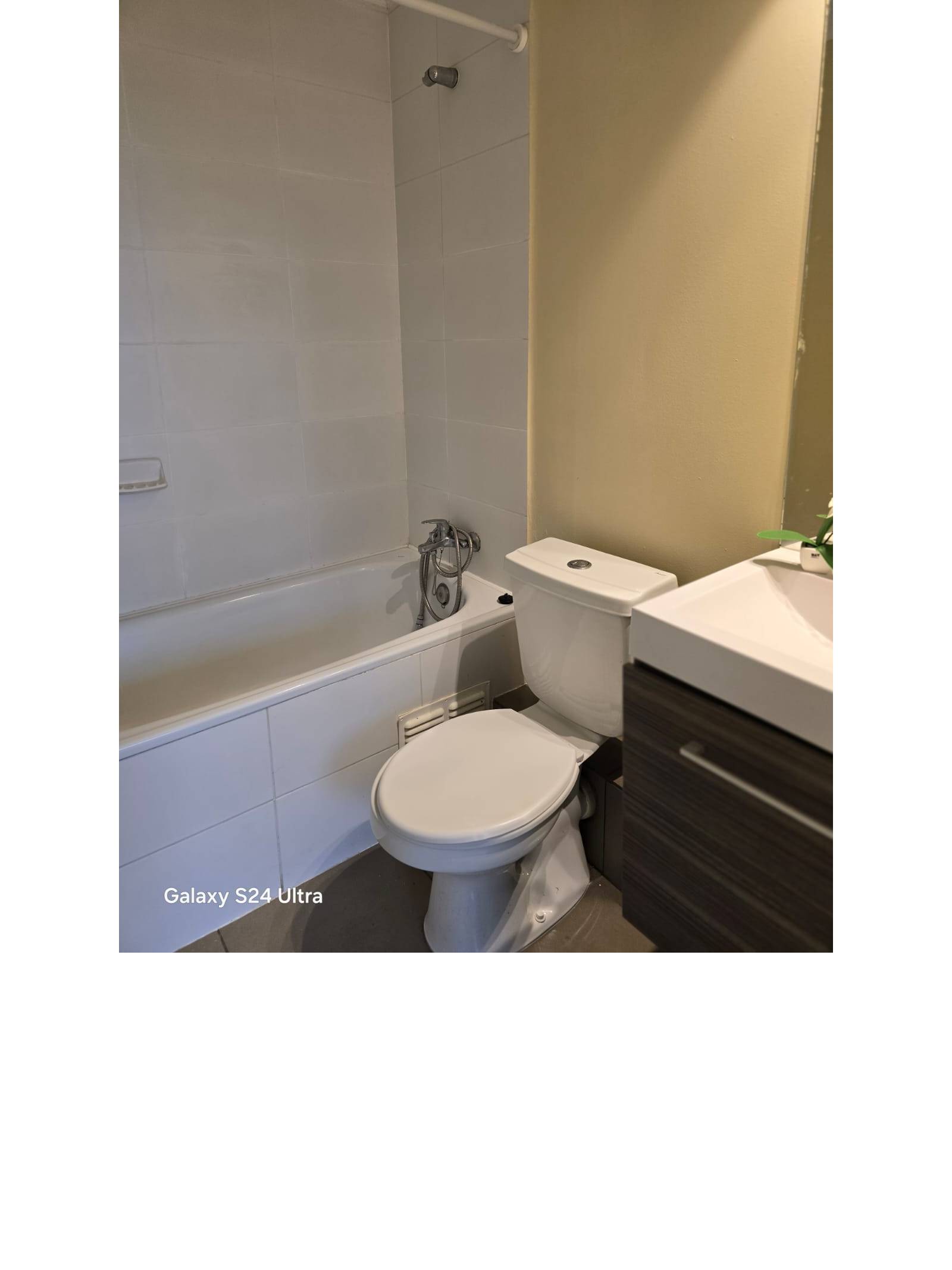 Baño completo con tina, sanitarios blancos y muros cerámicos.