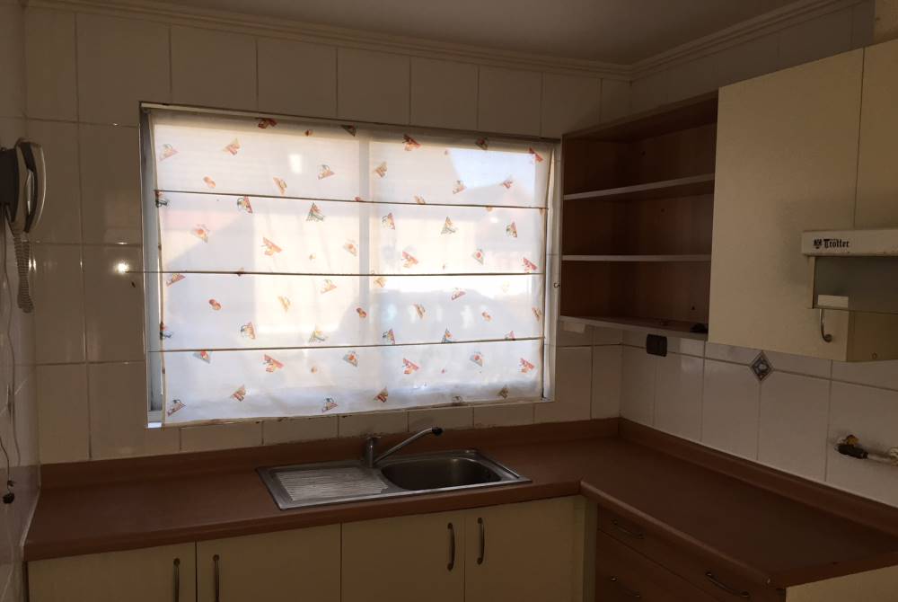 Mueble de cocina con lavaplatos y ventana al exterior.