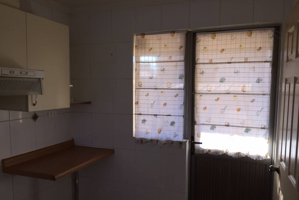 Mesón auxiliar y puerta con cortinas en cocina.