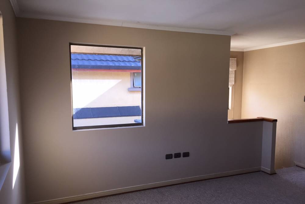 Dormitorio alfombrado con ventana hacia patio exterior.