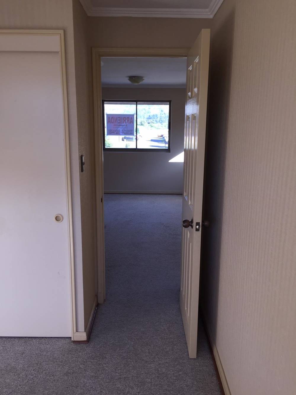 Puerta abierta hacia dormitorio con vista al exterior.