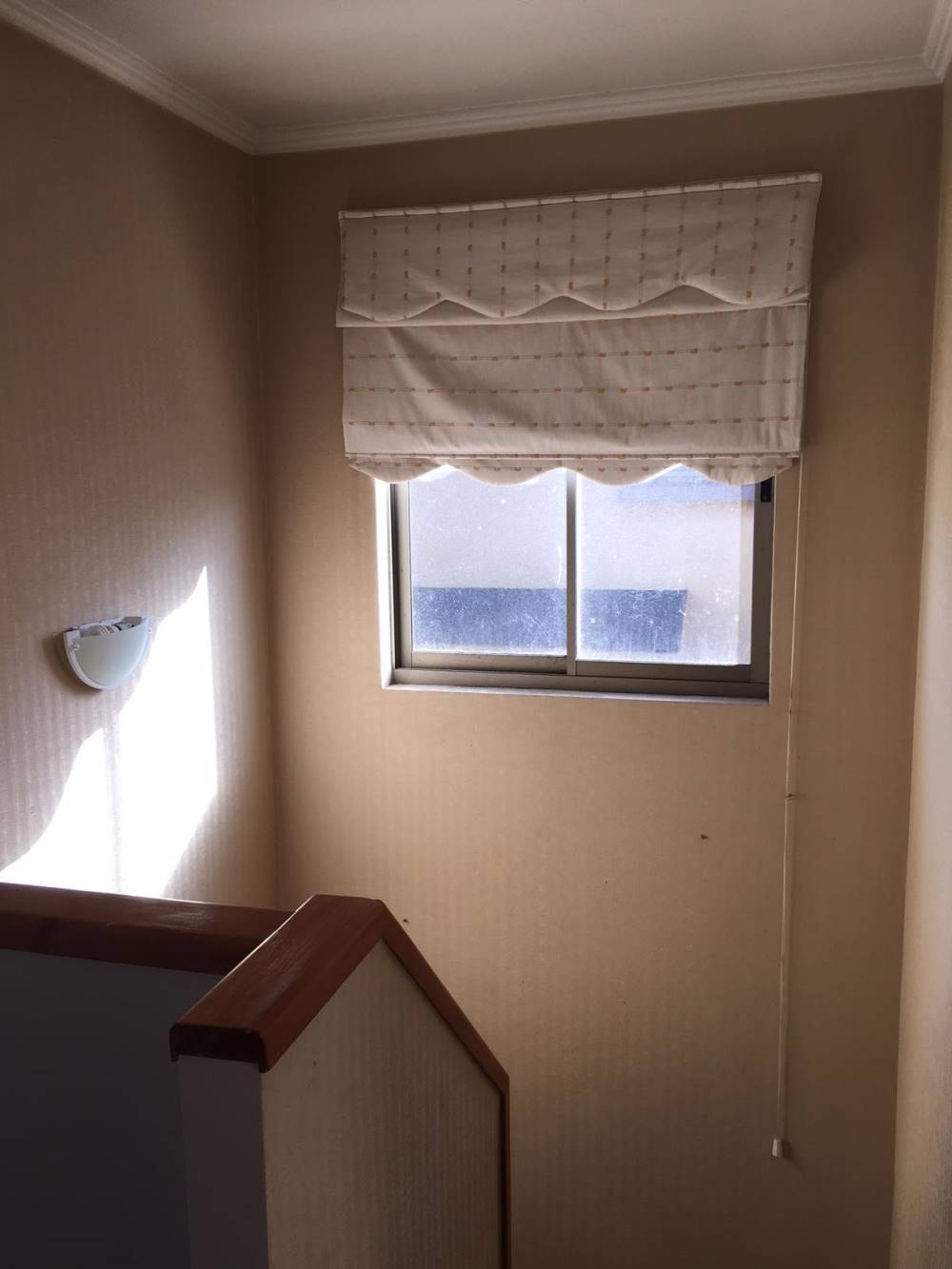 Descanso de escalera con ventana y estor.