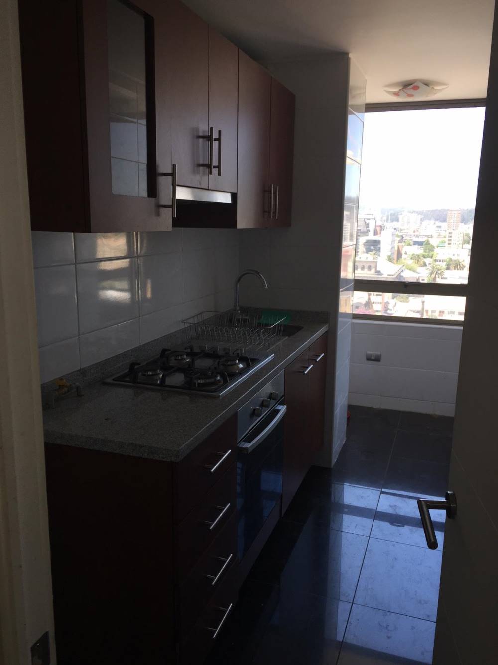 Cocina alargada con muebles de madera, encimera y ventana al fondo