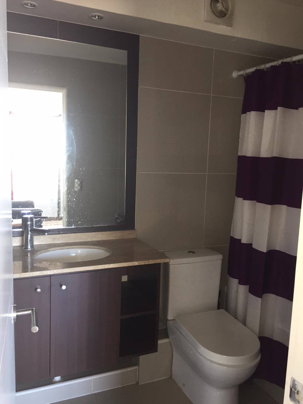 Baño completo con vanitorio oscuro, espejo amplio y tina con cortina