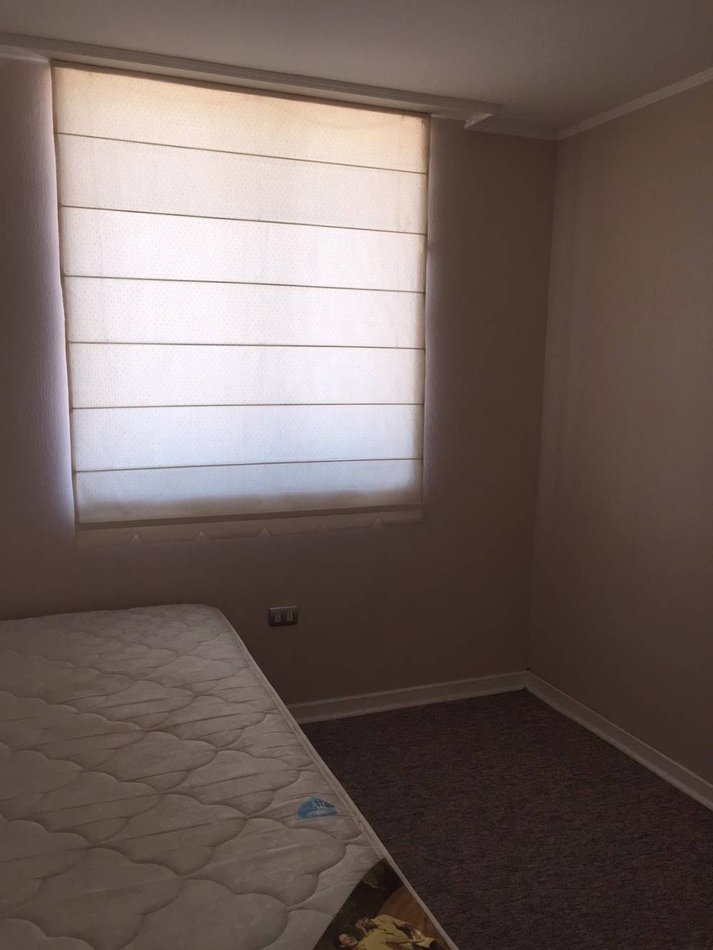 Dormitorio con cama y ventana con cortina tipo estor