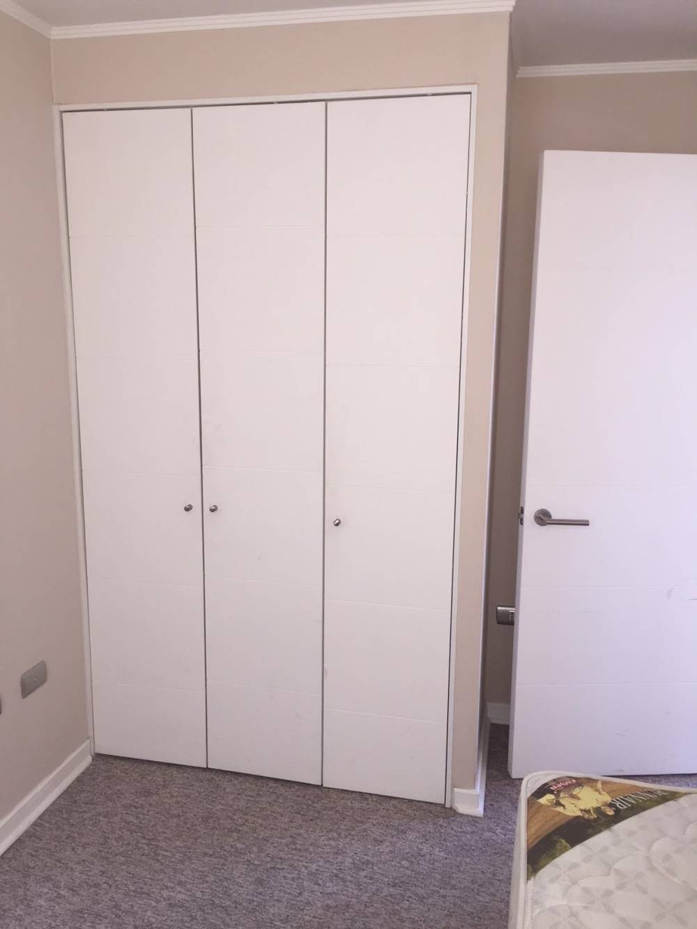 Clóset empotrado de tres puertas blancas en dormitorio