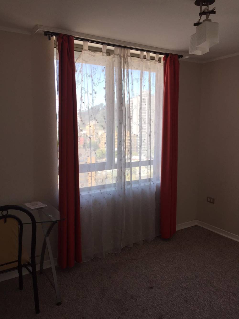 Dormitorio con ventanal amplio, cortinas y alfombra en el piso