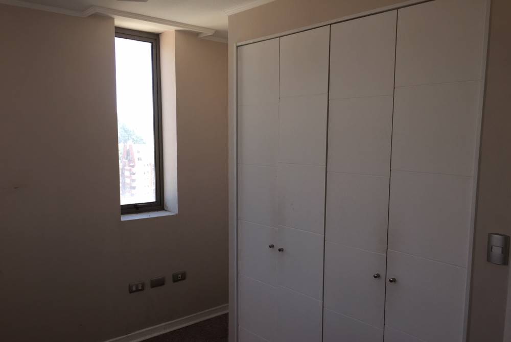 Dormitorio con amplio clóset blanco y ventana vertical