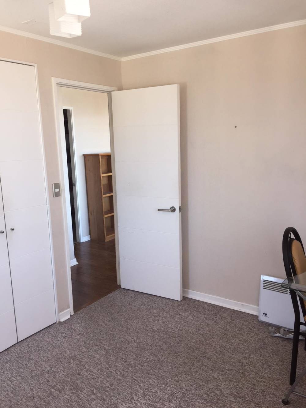 Dormitorio con puerta abierta hacia el pasillo y calefactor de pared