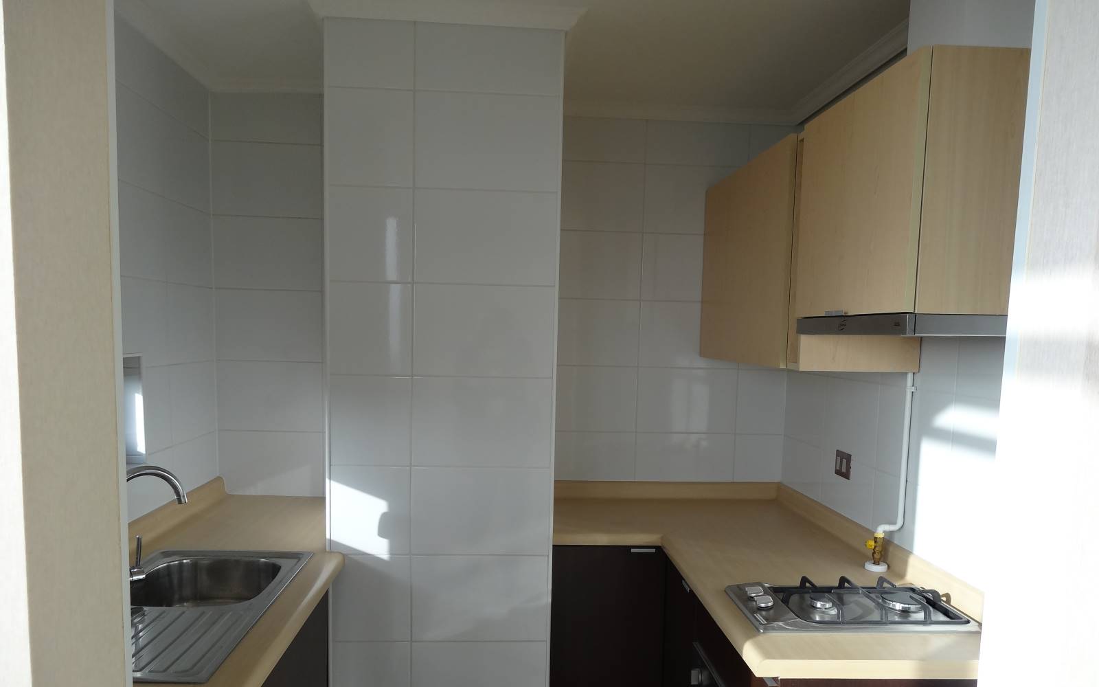 Cocina con mesones, encimera a gas y lavaplatos integrado.