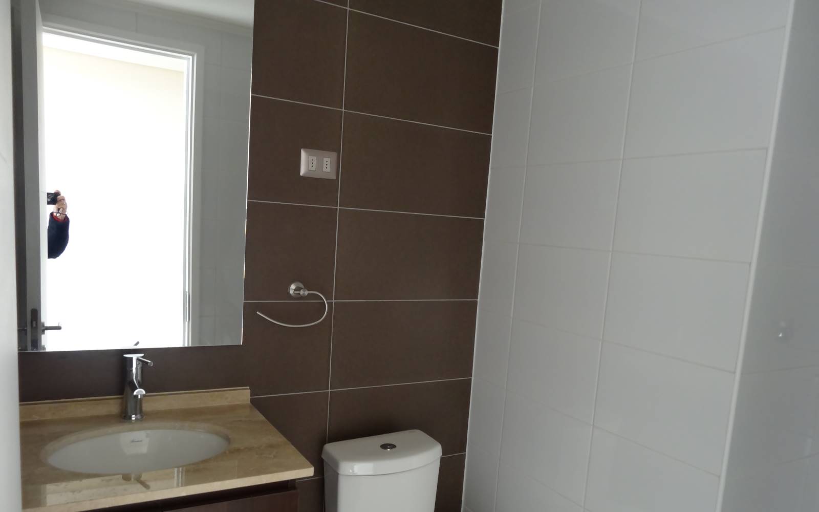 Baño con vanitorio, espejo amplio y sanitario blanco.