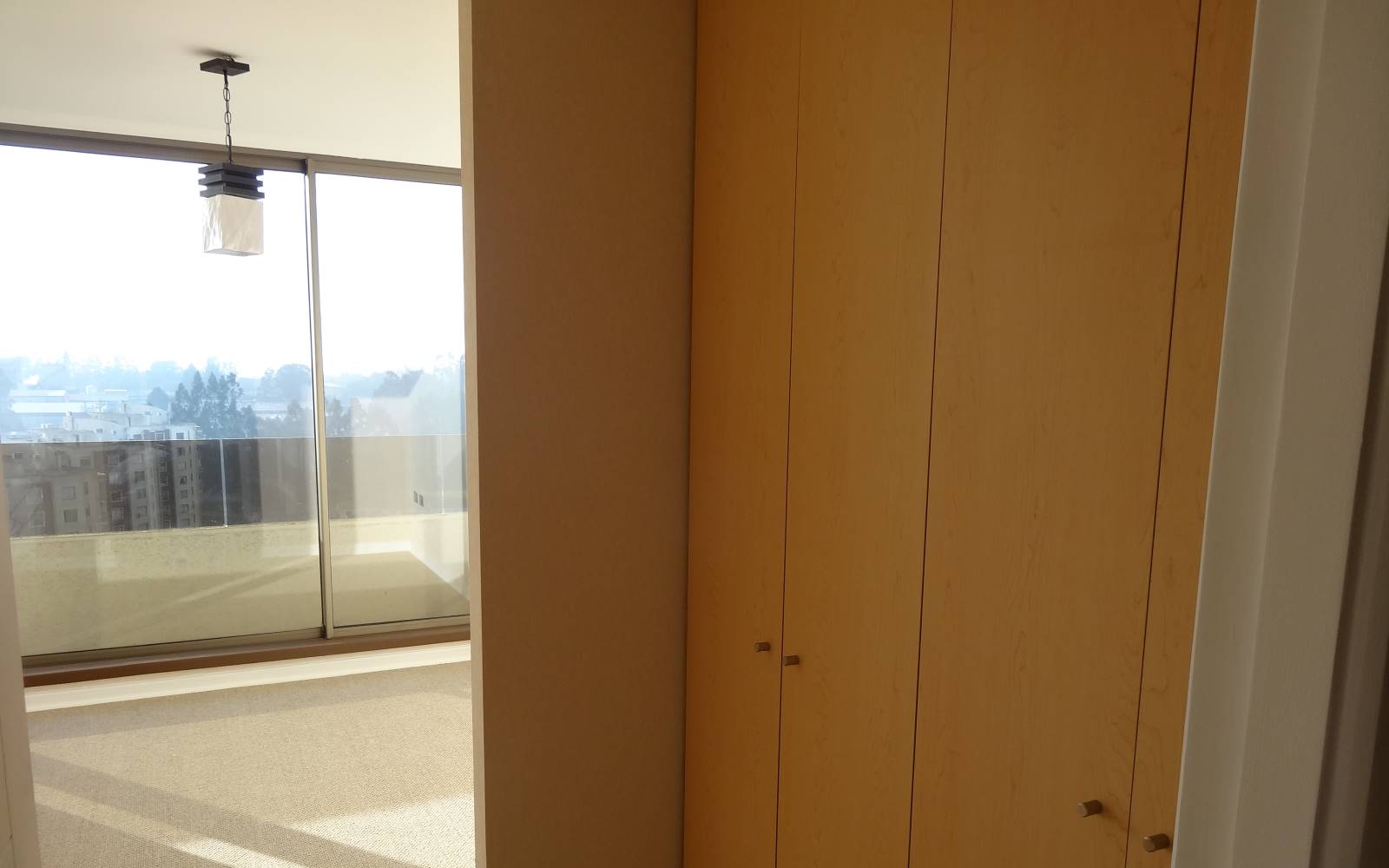 Dormitorio con clóset empotrado y ventanal hacia el balcón.