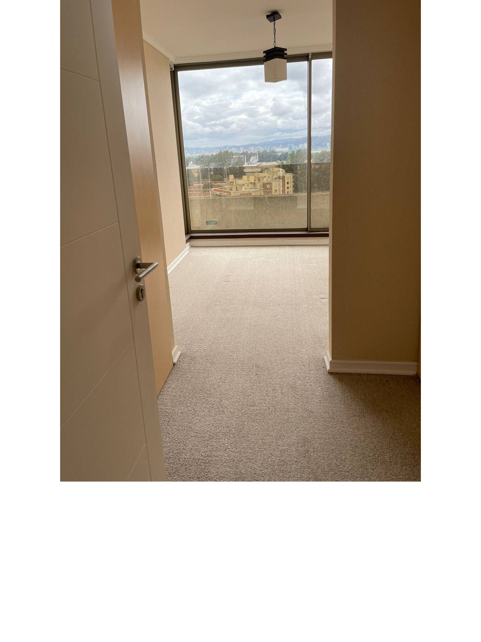 Dormitorio alfombrado con gran ventanal y vista panorámica.