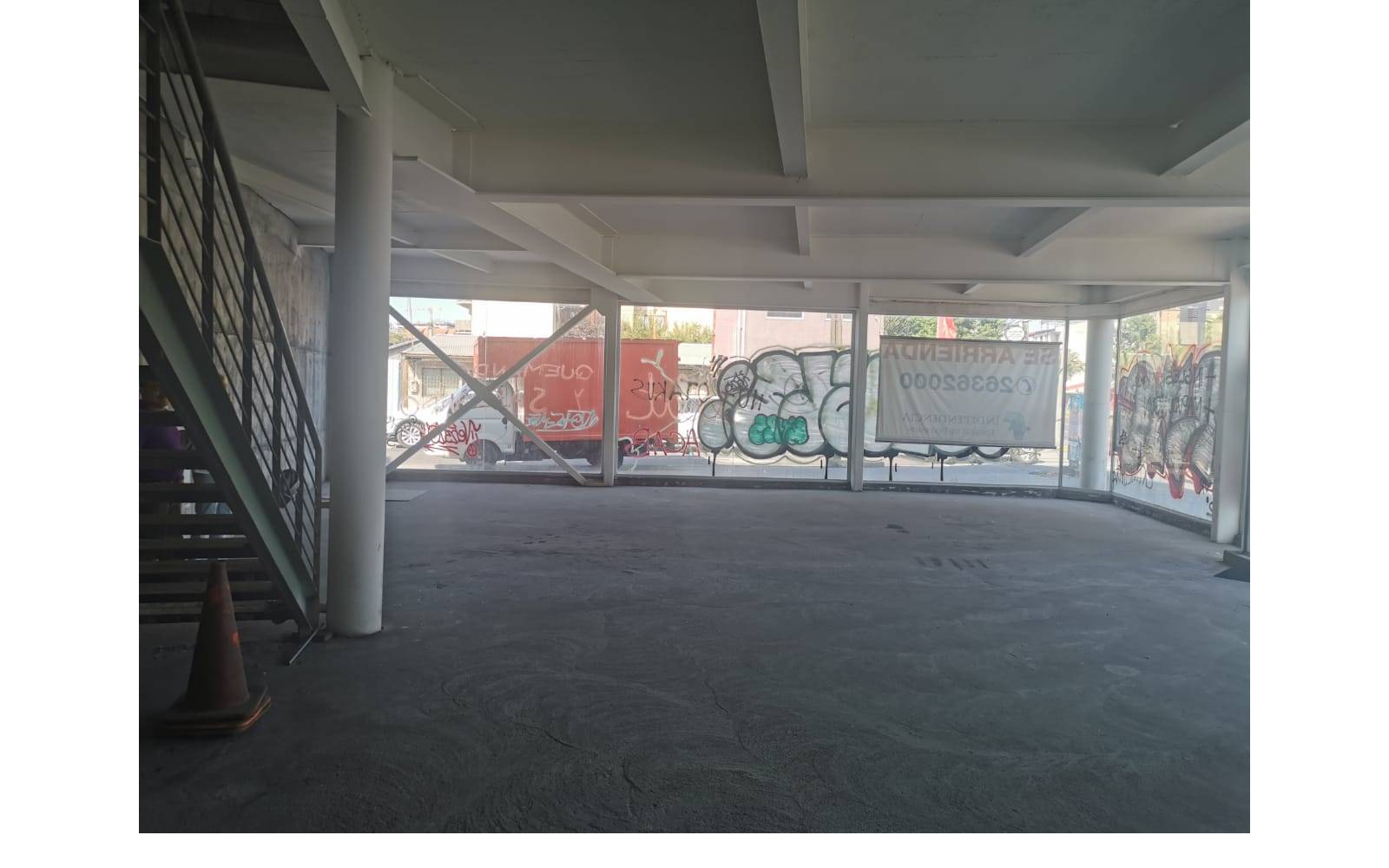 Planta baja despejada con escalera metálica y pilares estructurales