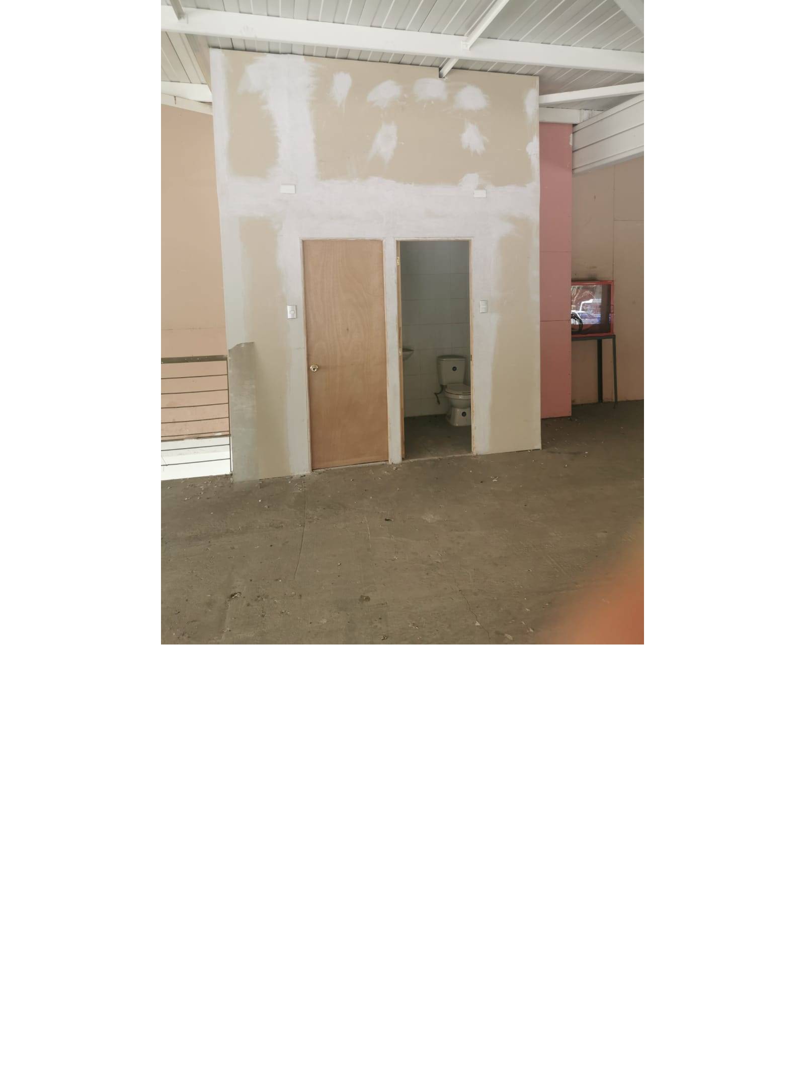 Sector de baños en obra con tabiquería y puerta de madera