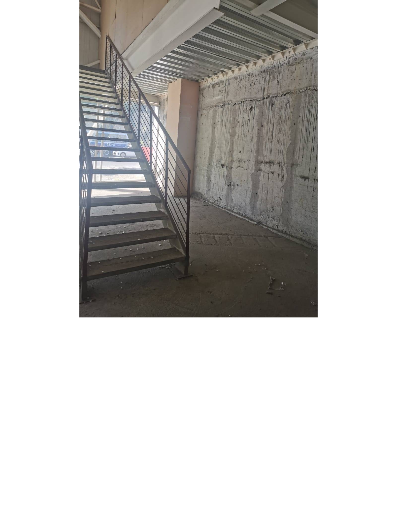 Escalera metálica de acceso con muro de hormigón al fondo