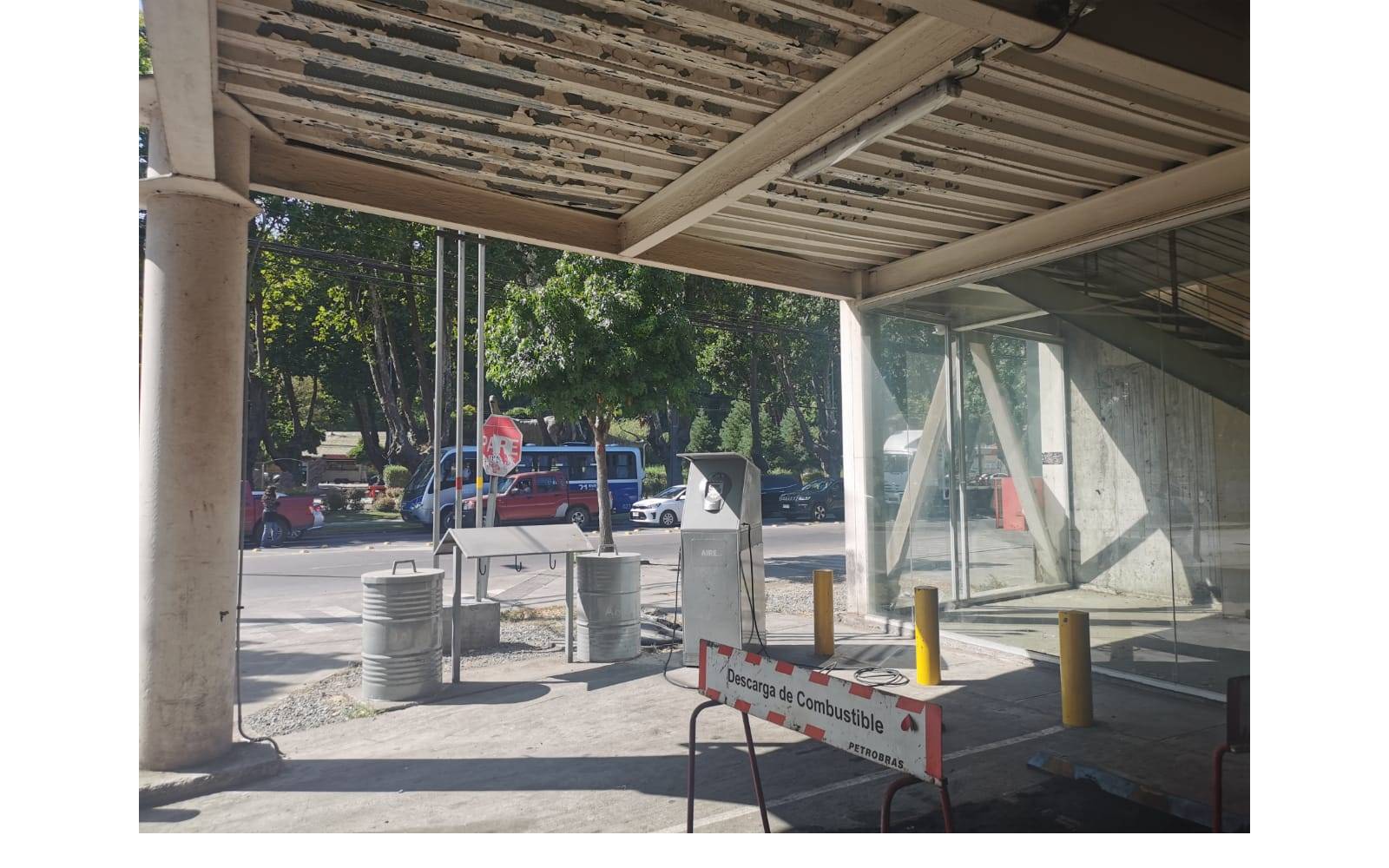 Acceso vehicular techado exterior con pilares y área de descarga