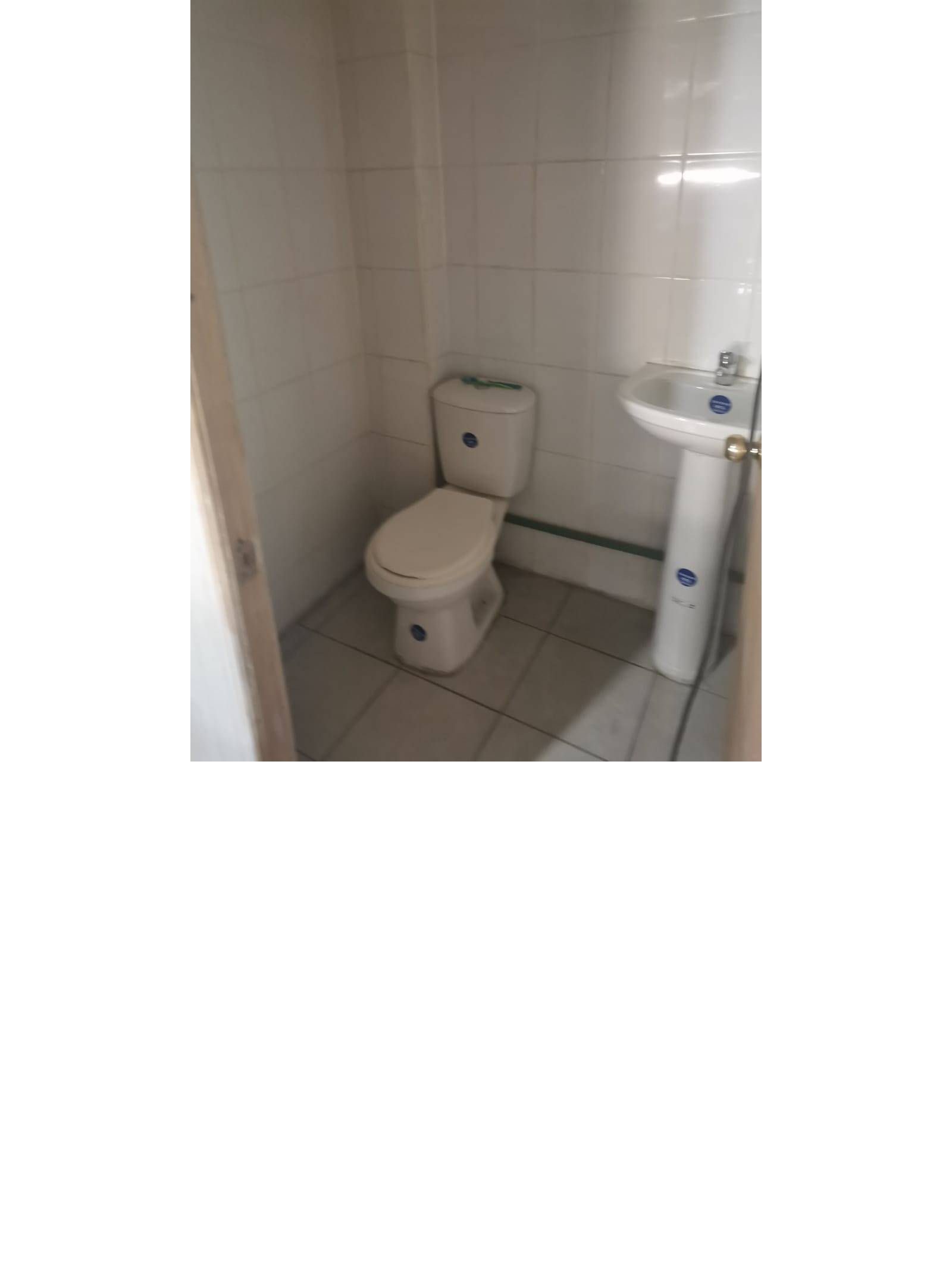 Baño sencillo con inodoro, lavamanos y muros de cerámica