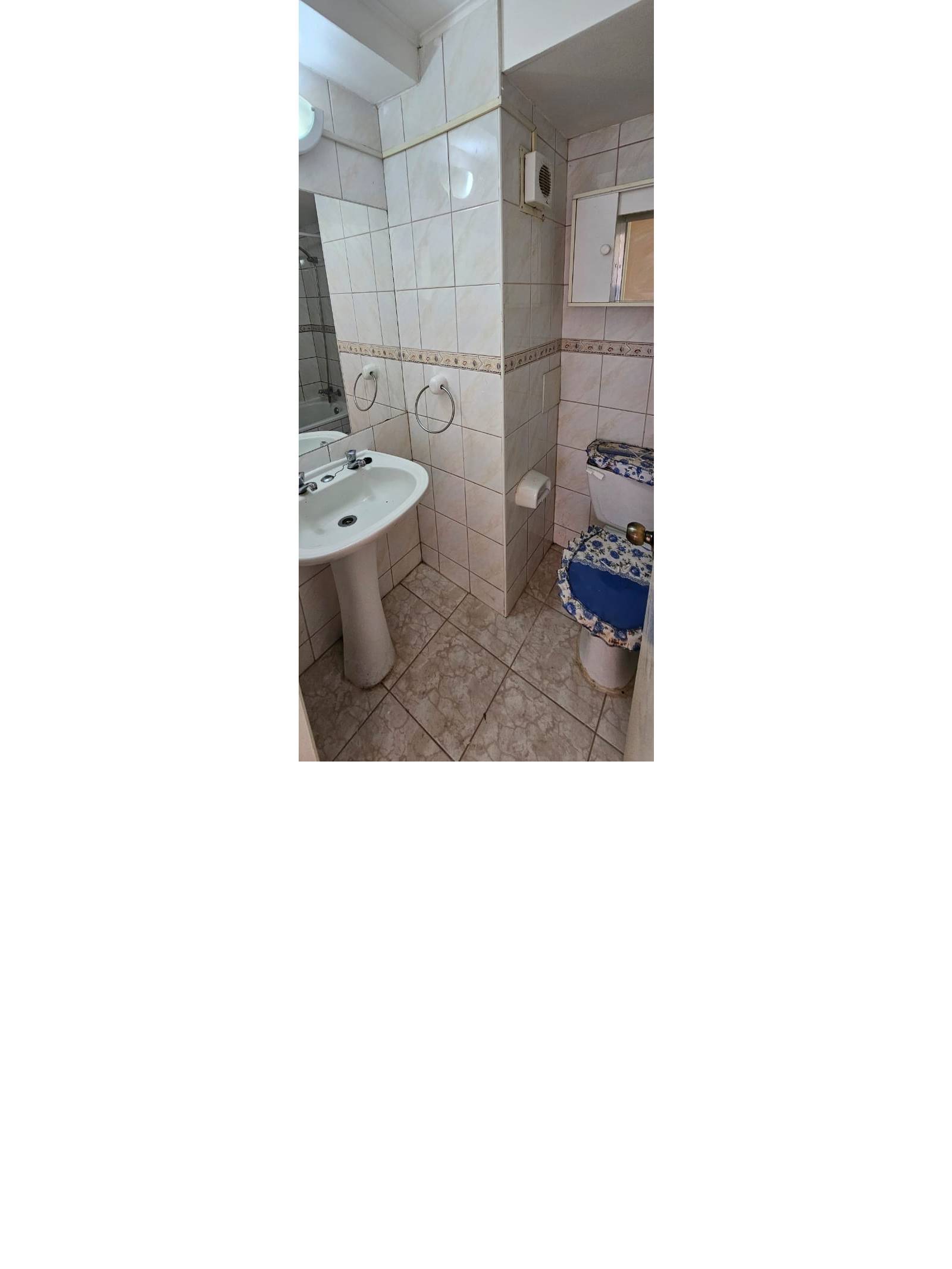 Baño con lavamanos de pedestal sanitario y paredes azulejadas