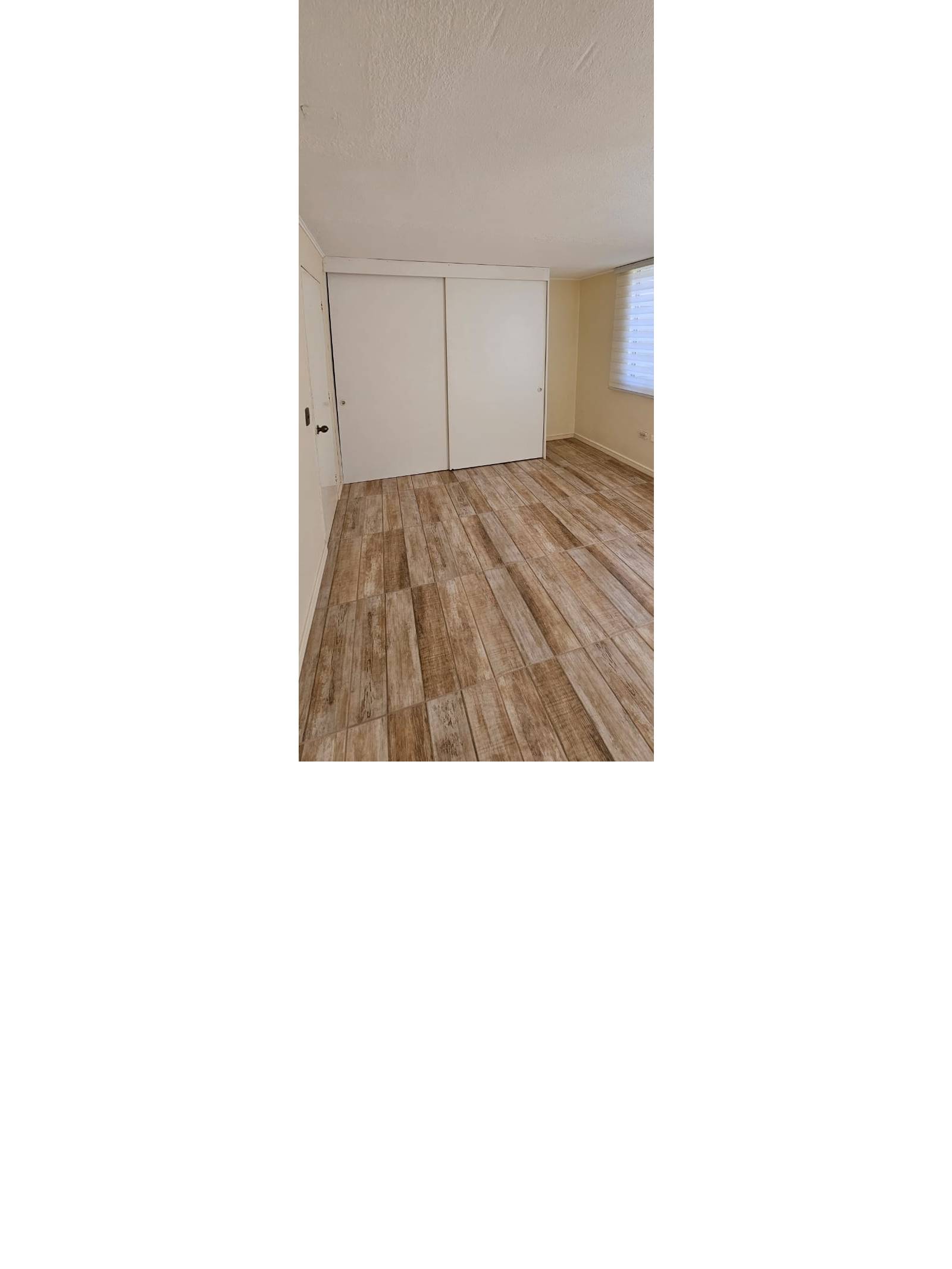 Dormitorio vacío con clóset empotrado y piso cerámico