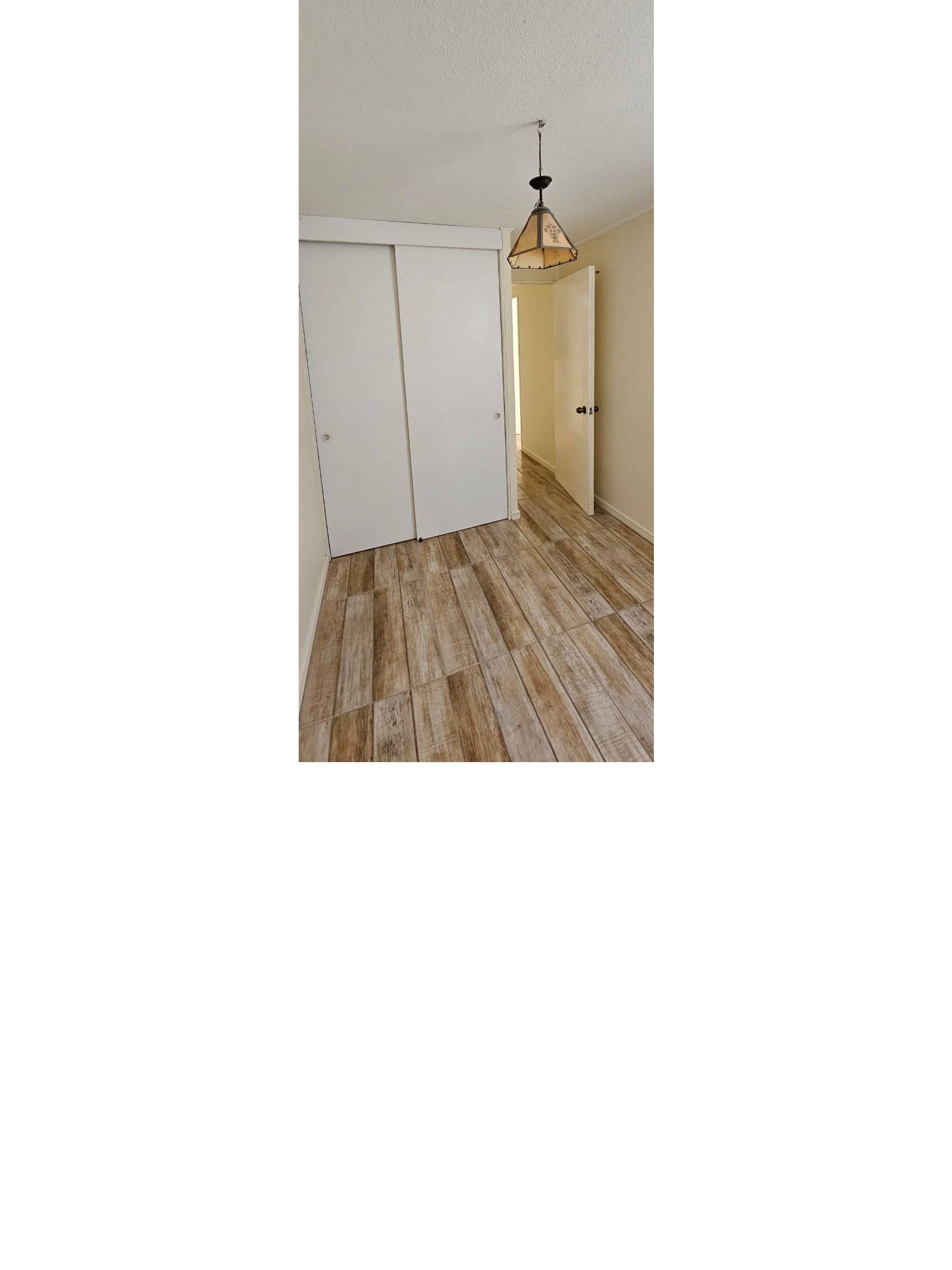 Habitación con lámpara colgante y clóset de puertas corredizas