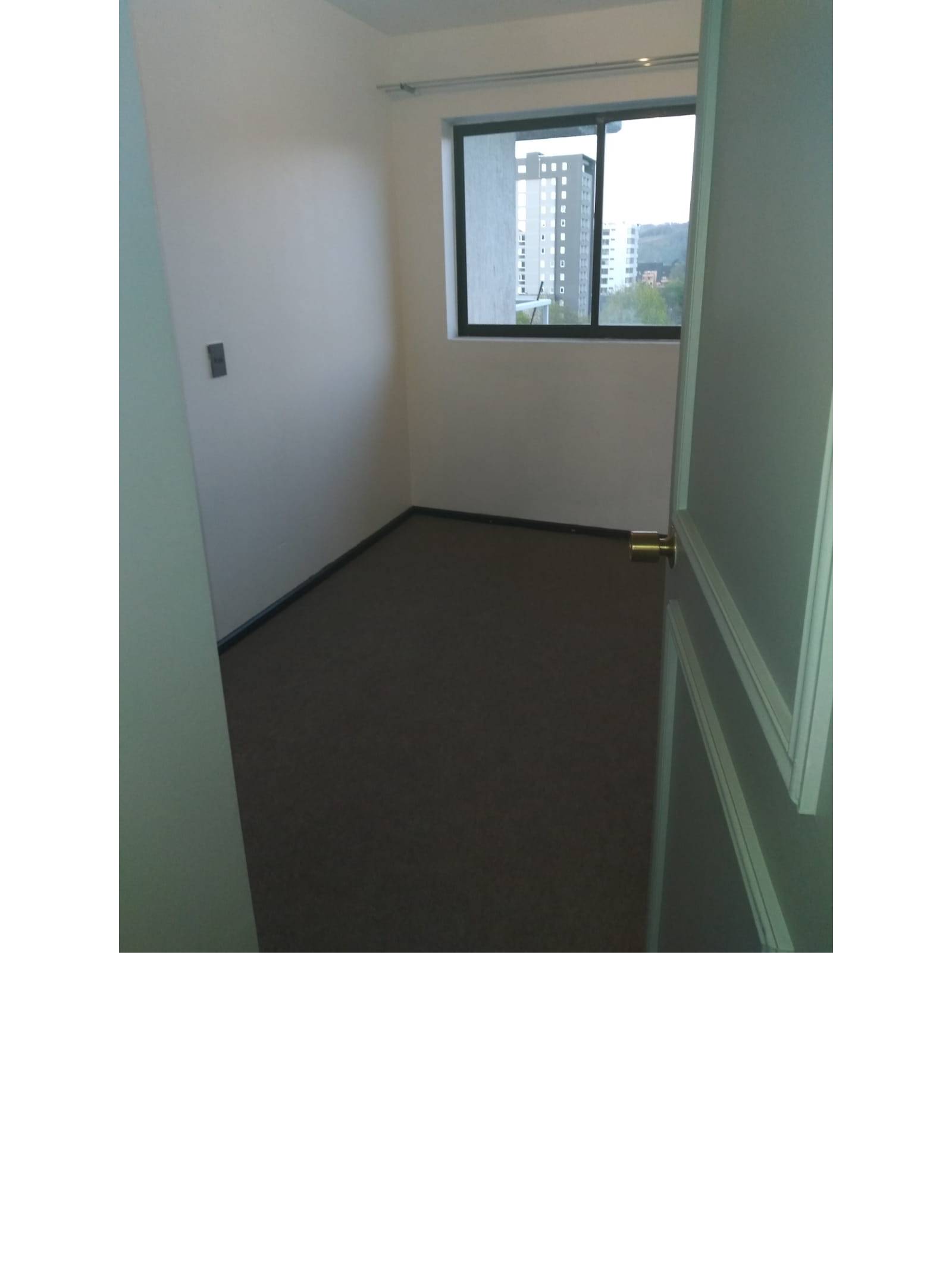 Dormitorio alfombrado con ventana hacia la ciudad
