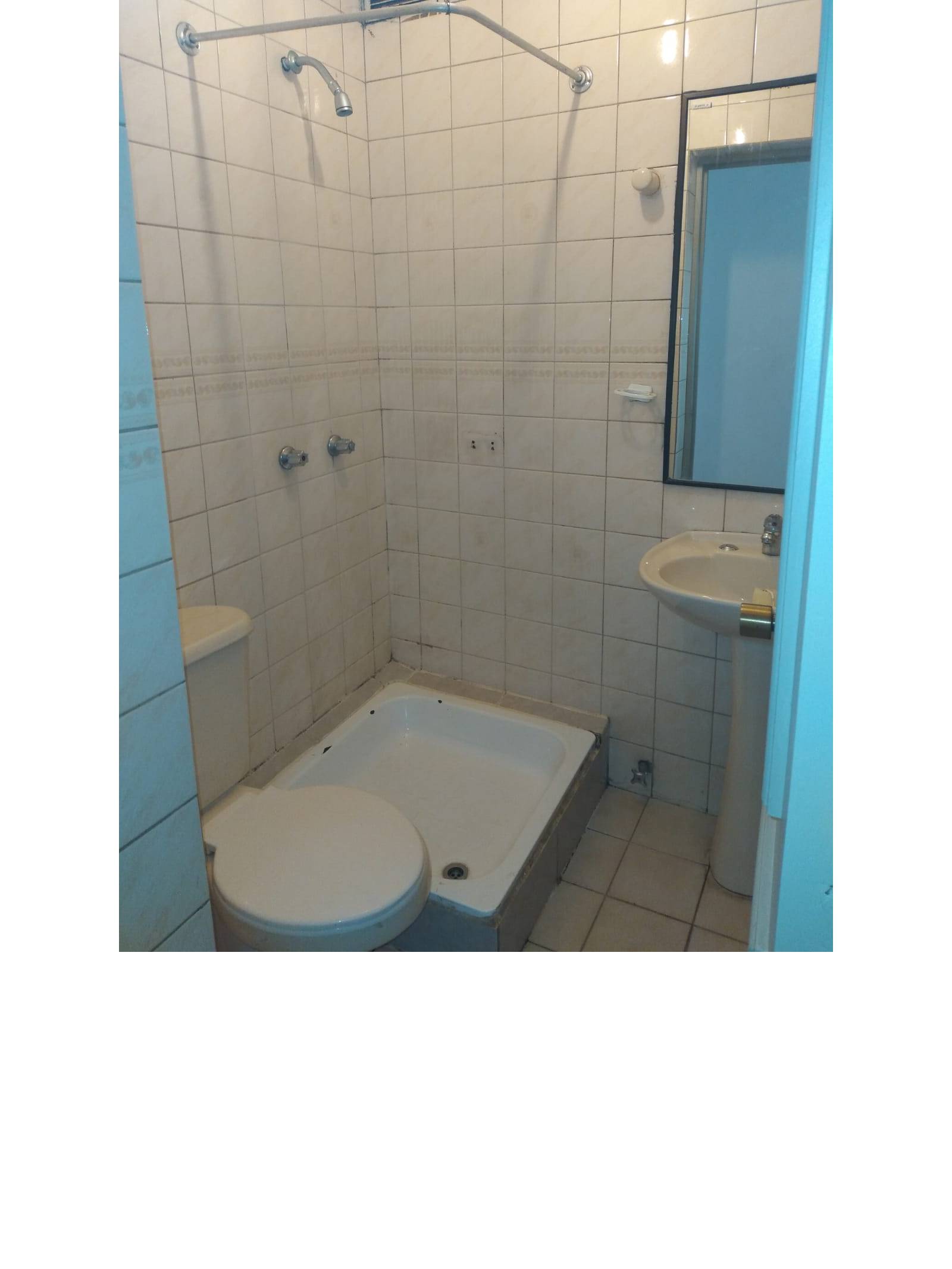 Baño con azulejos blancos, receptáculo de ducha y lavamanos