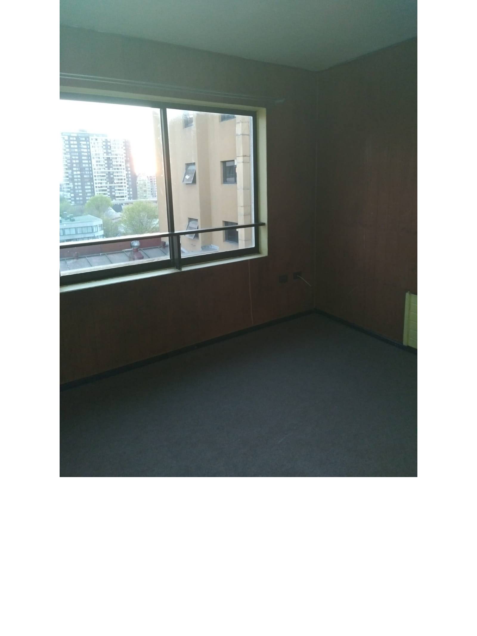 Dormitorio con paredes paneladas y ventanal con vista urbana