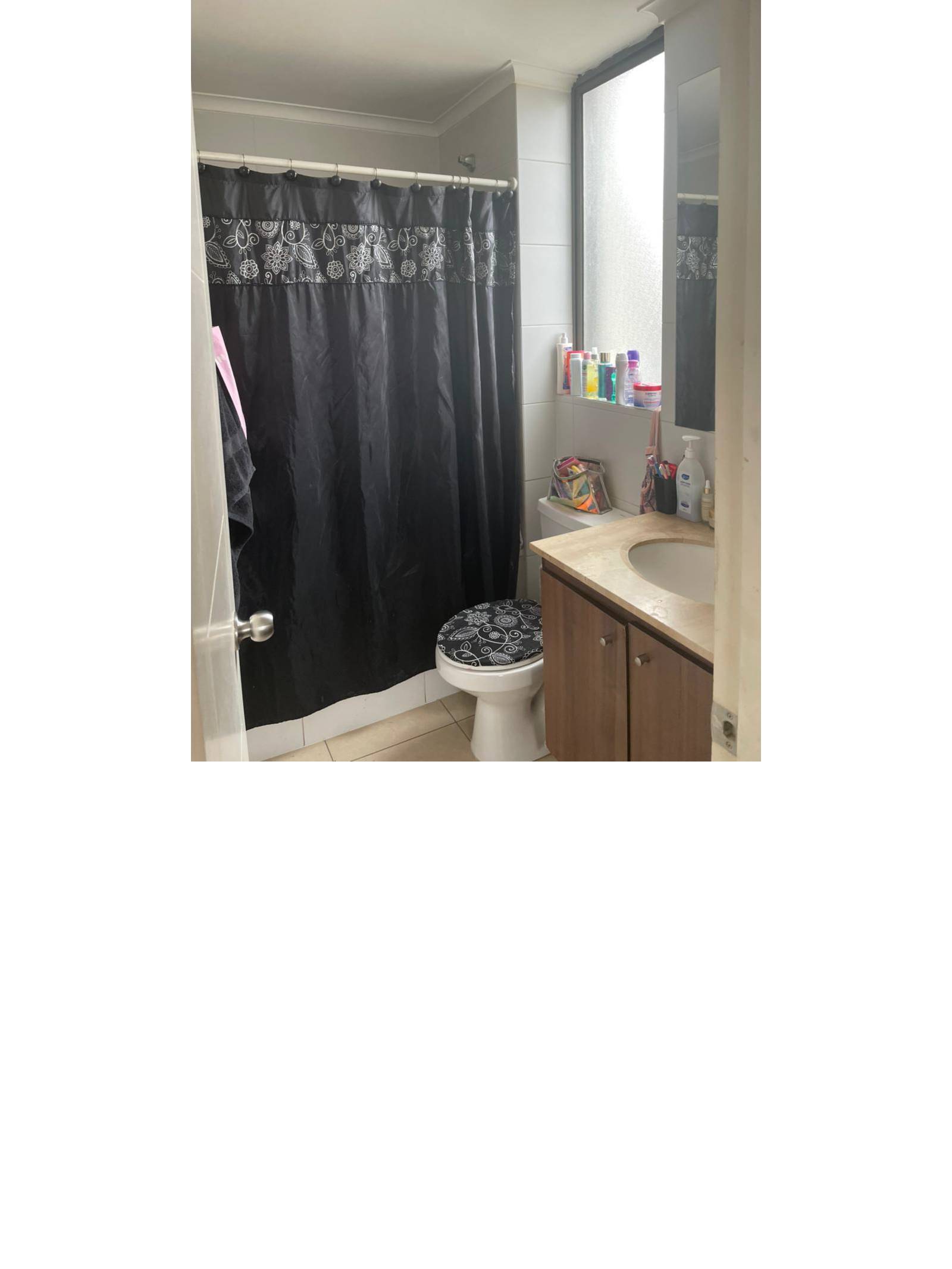 Baño con vanitorio de madera cortina oscura e inodoro