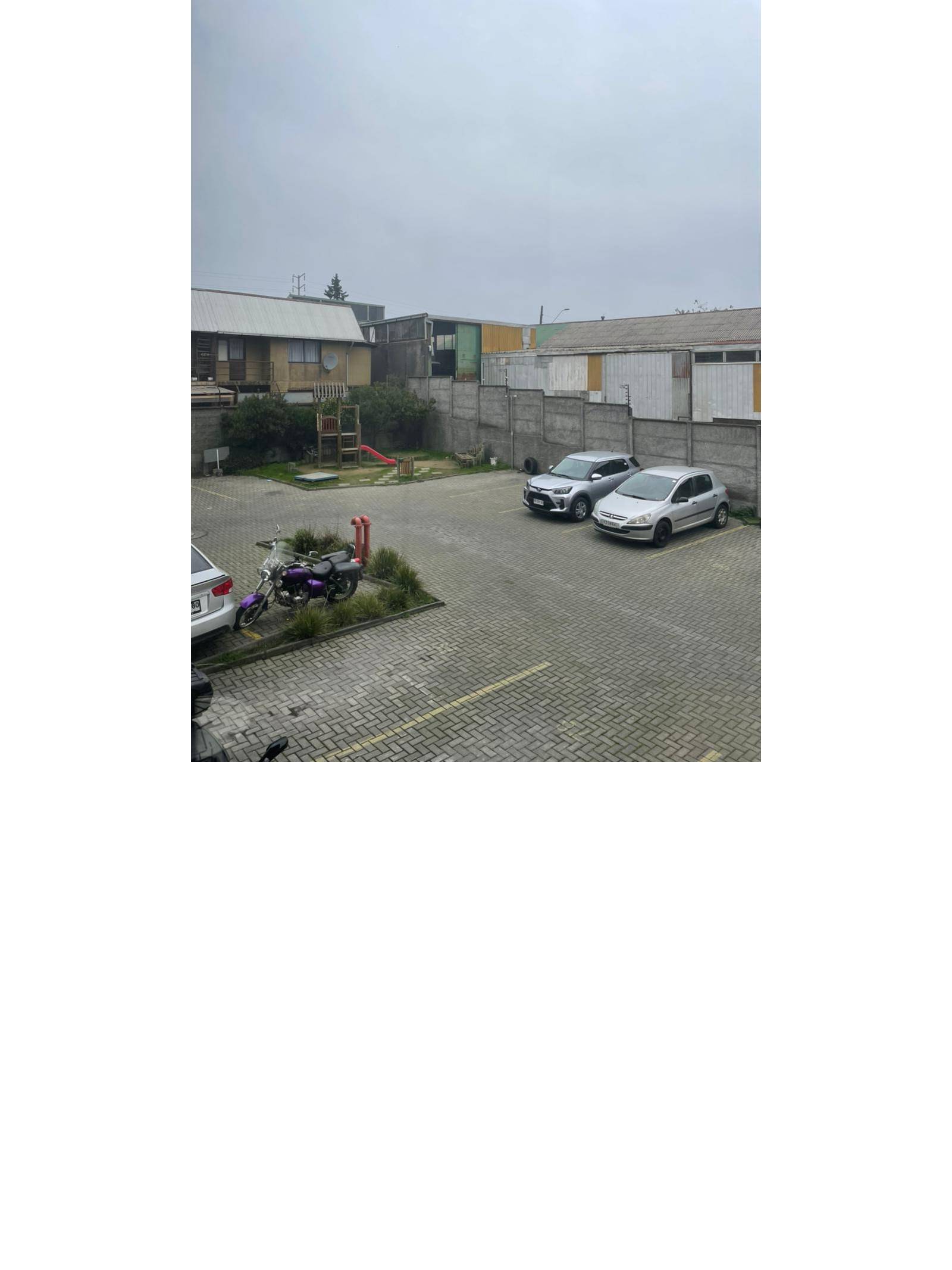 Vista exterior hacia patio de estacionamientos y juegos infantiles