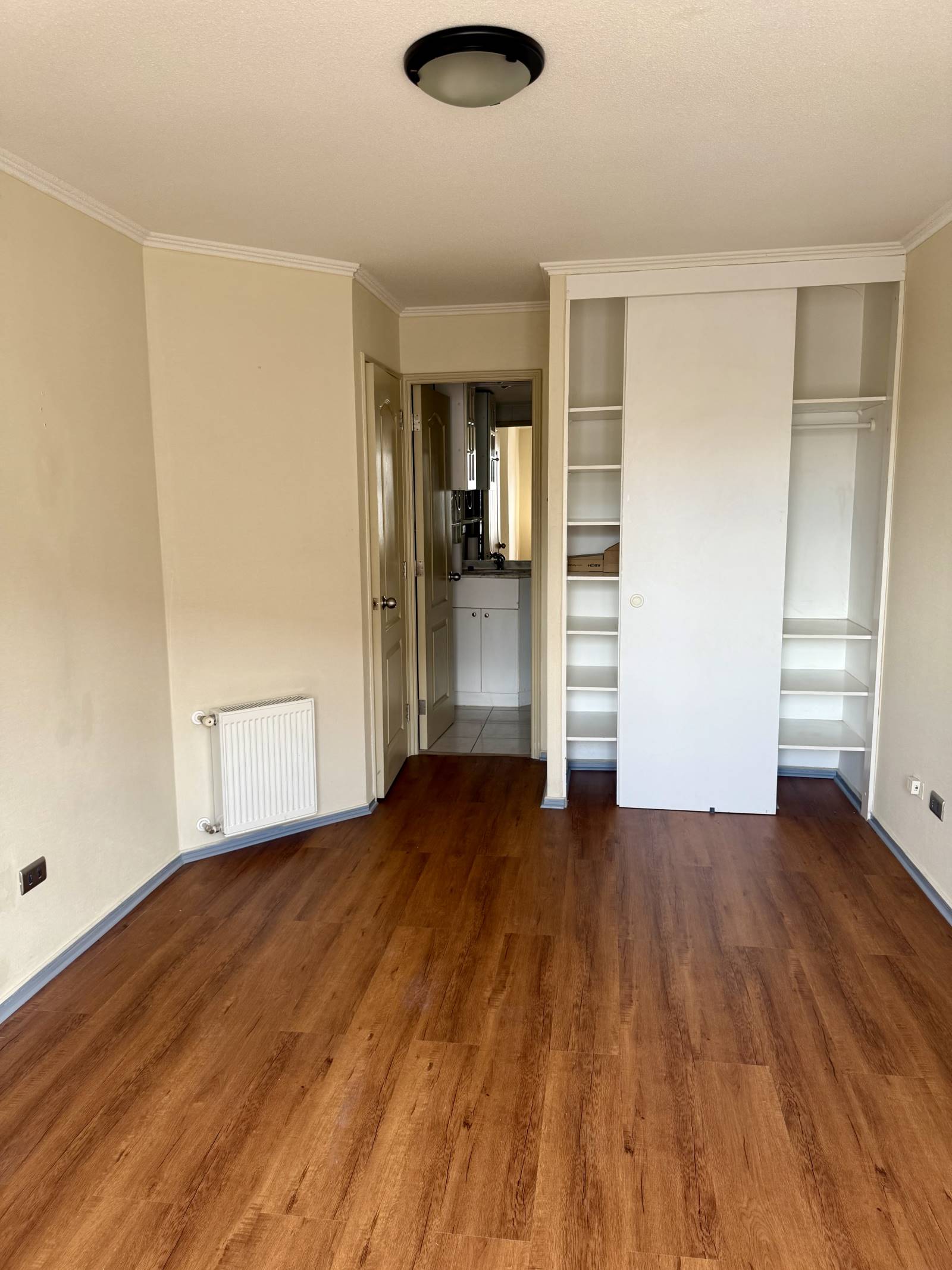 Dormitorio con clóset empotrado, radiador y acceso al baño.