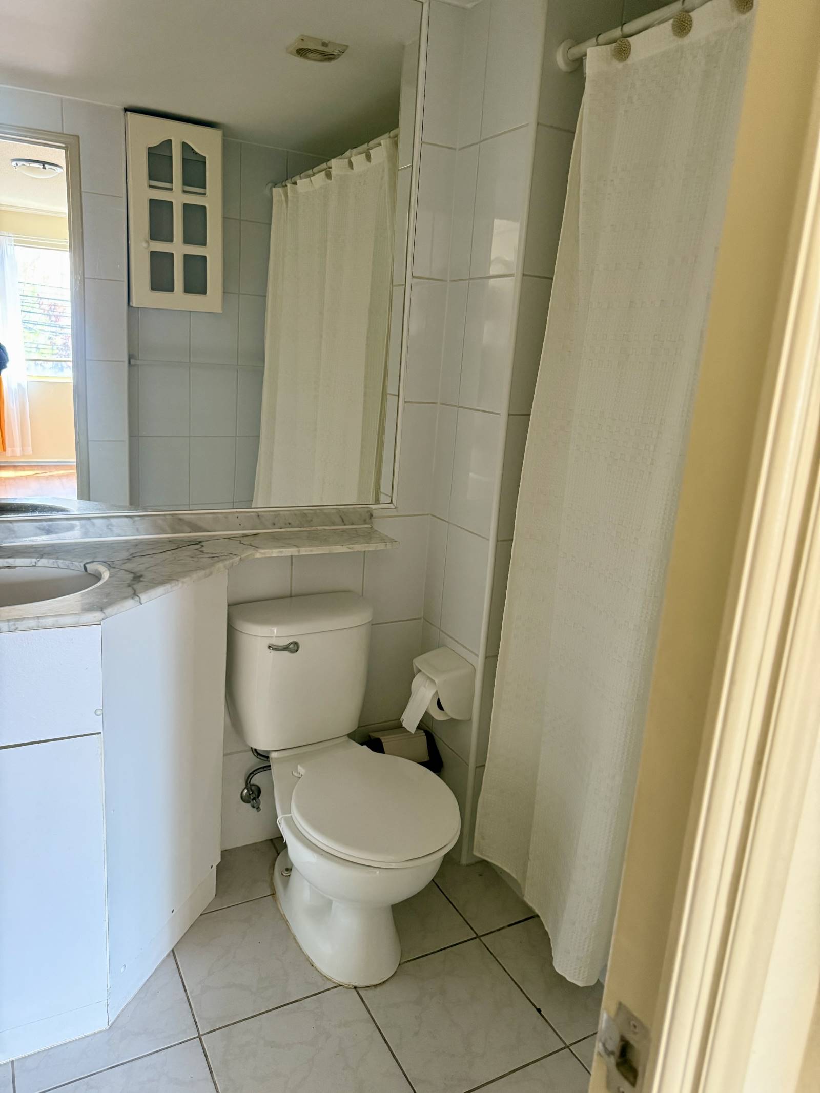 Baño completo con vanitorio, inodoro y tina con cortina.