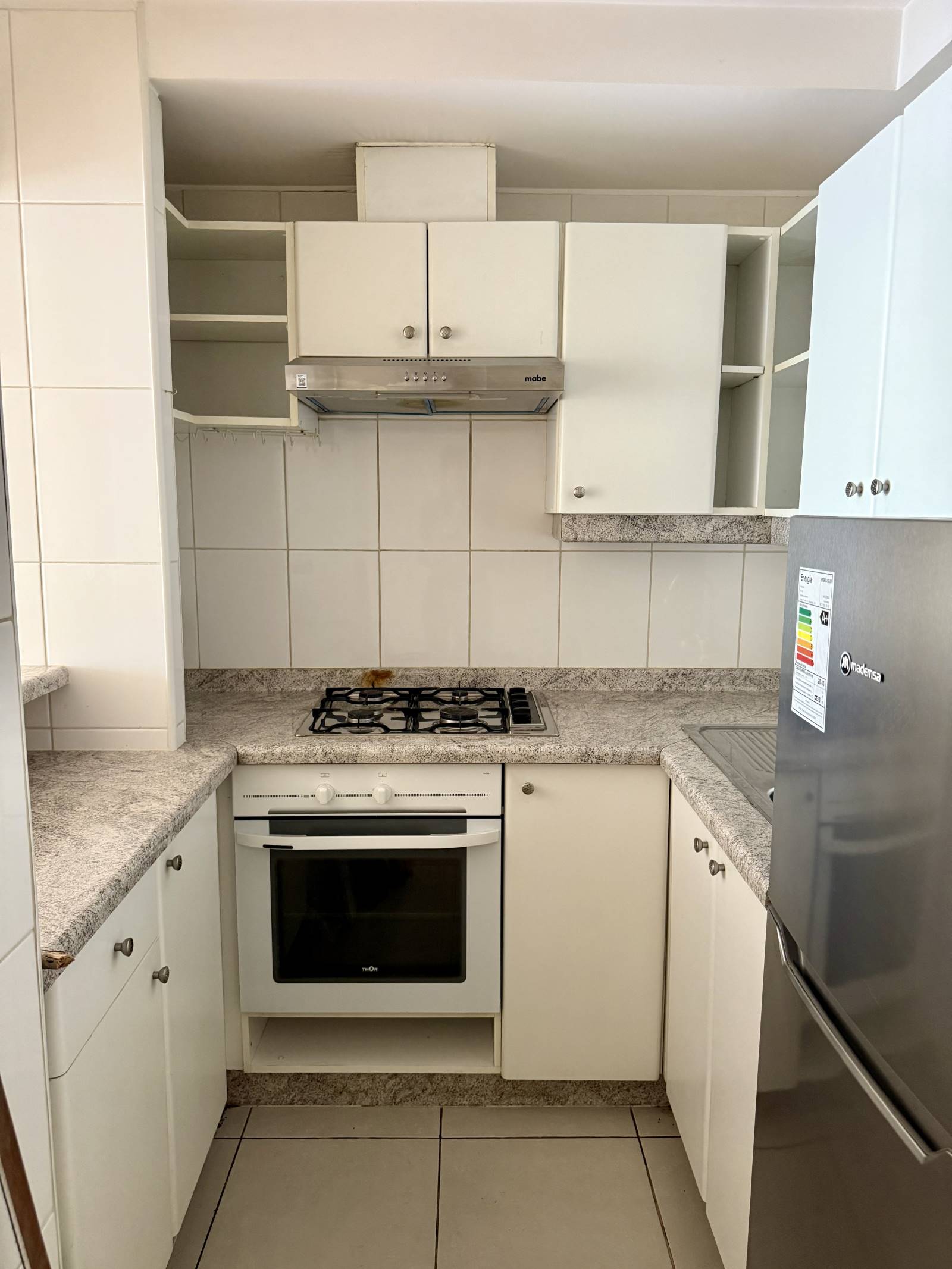 Cocina equipada con encimera a gas, horno y muebles empotrados.