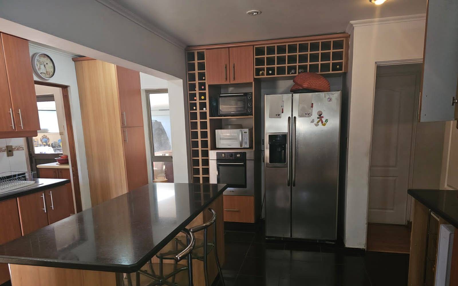 Cocina con isla central, refrigerador de acero y torre de hornos.