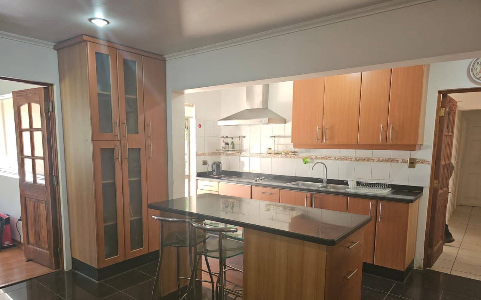 Mobiliario de cocina en madera con encimera y campana extractora.