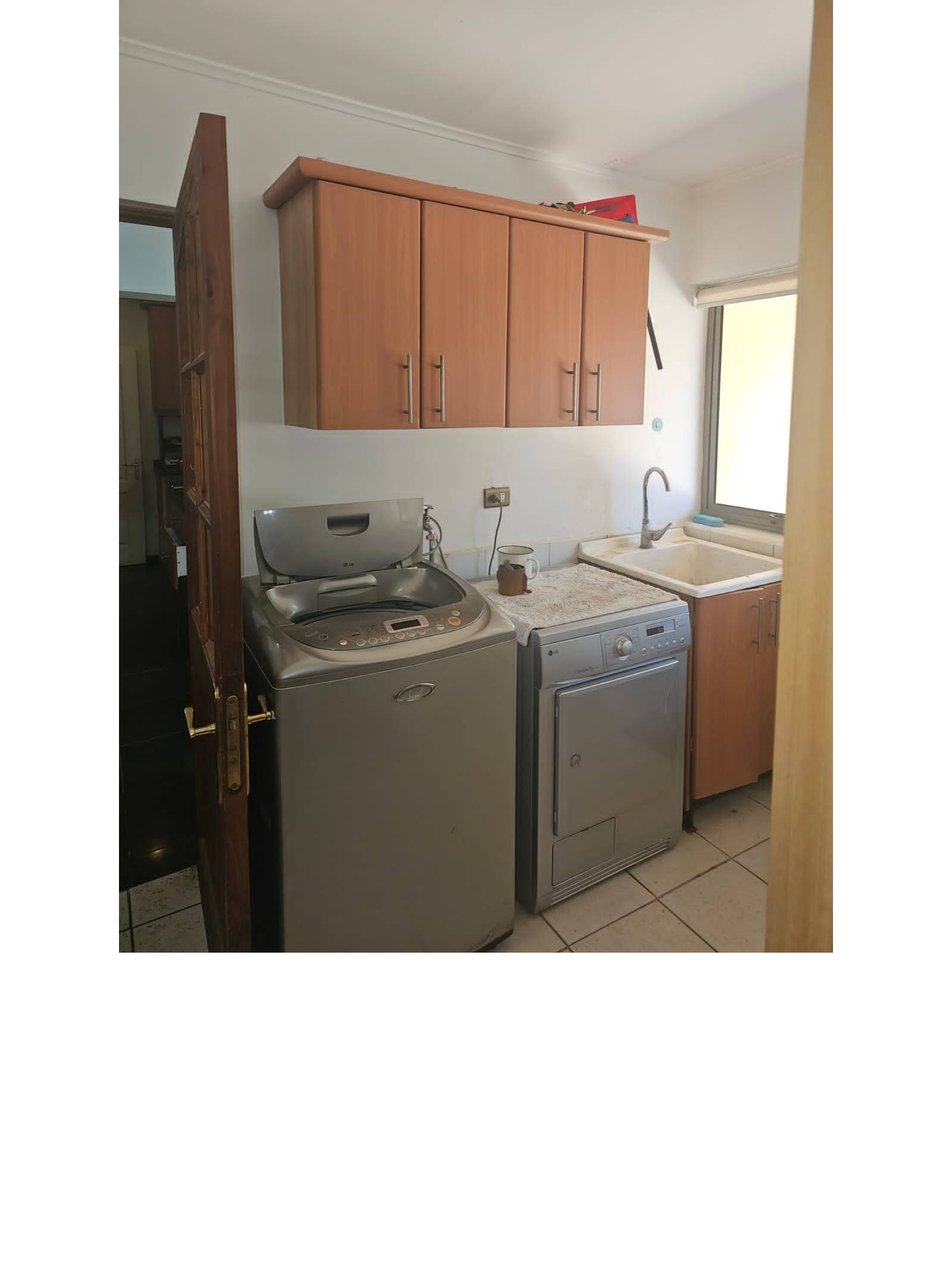 Logia interior con lavadora, secadora y muebles aéreos.