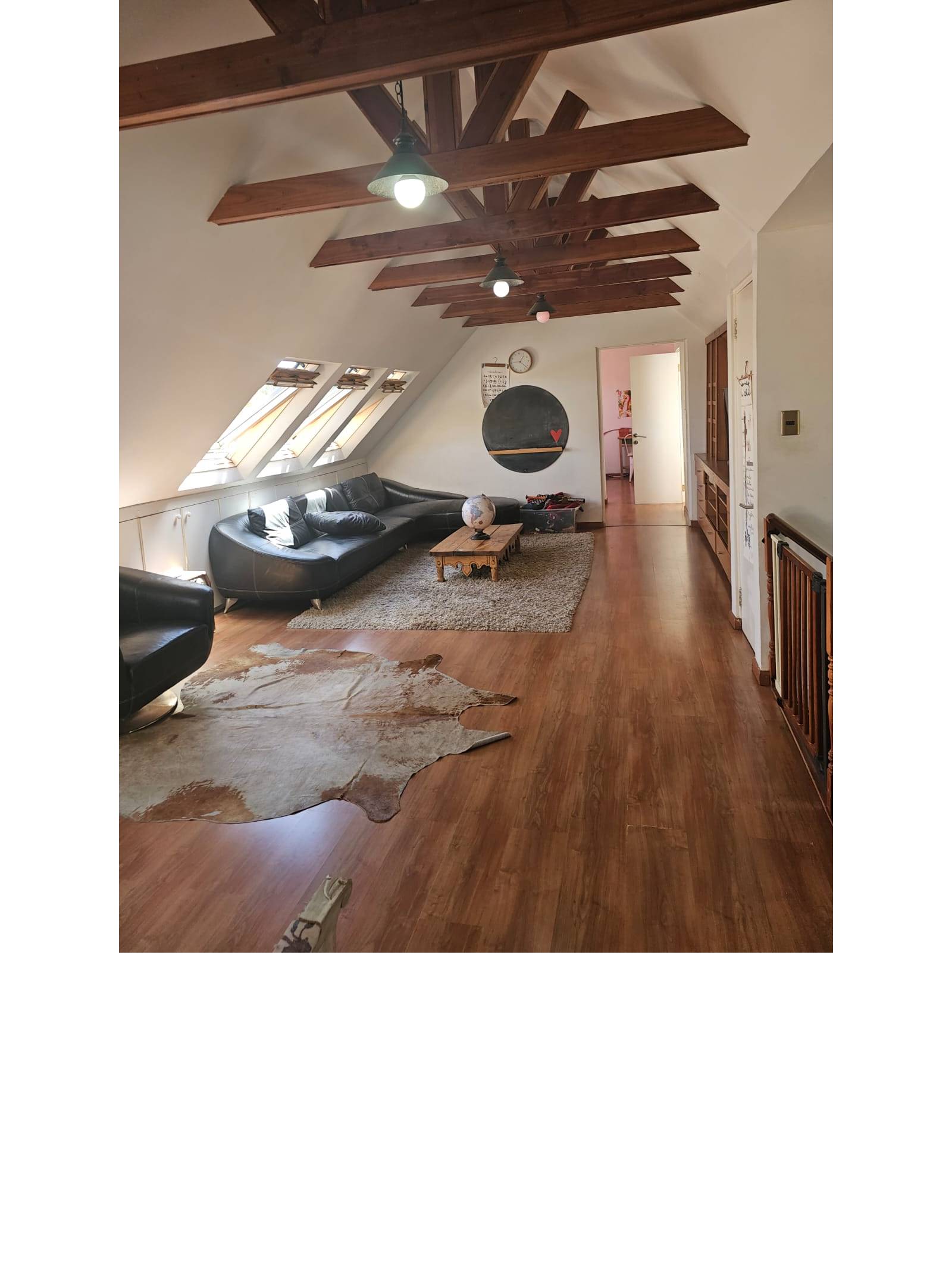 Sala de estar abuhardillada con vigas a la vista.