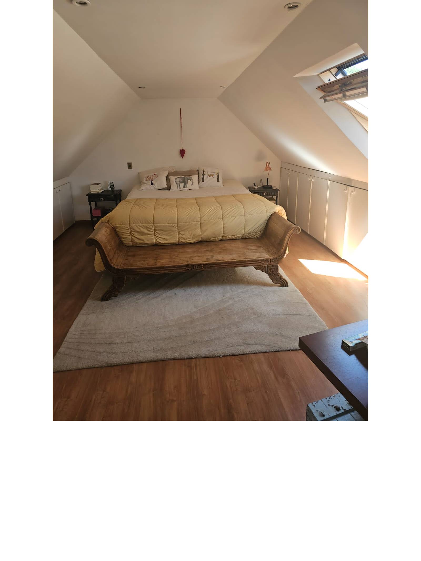 Dormitorio matrimonial abuhardillado con ventana en el techo.