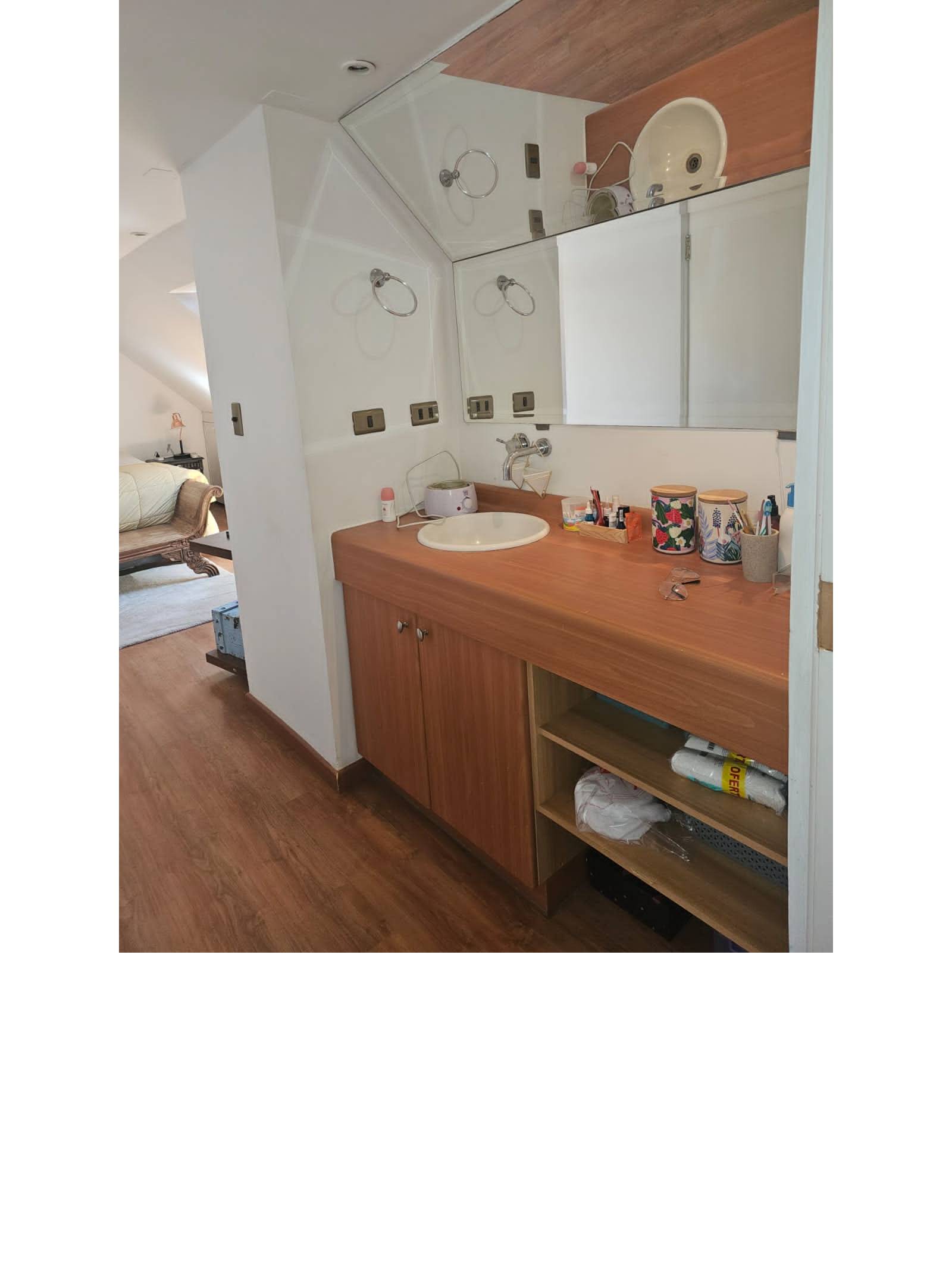Vanitorio amplio de baño en suite con mueble de madera.