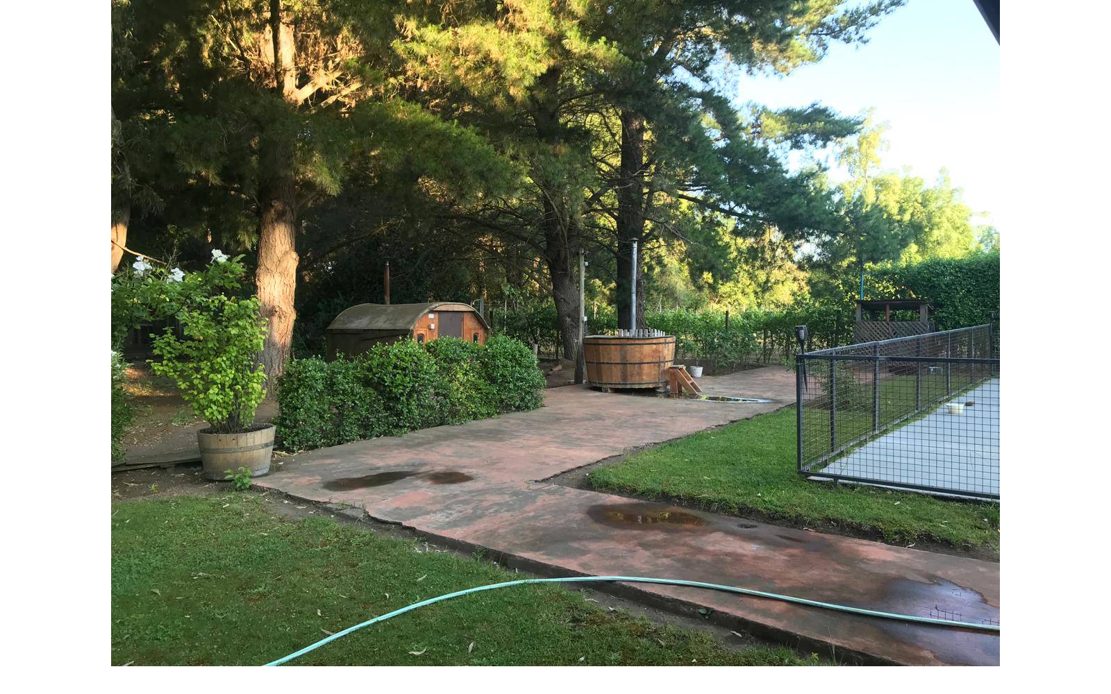 Patio con tinaja de madera caliente y área verde.