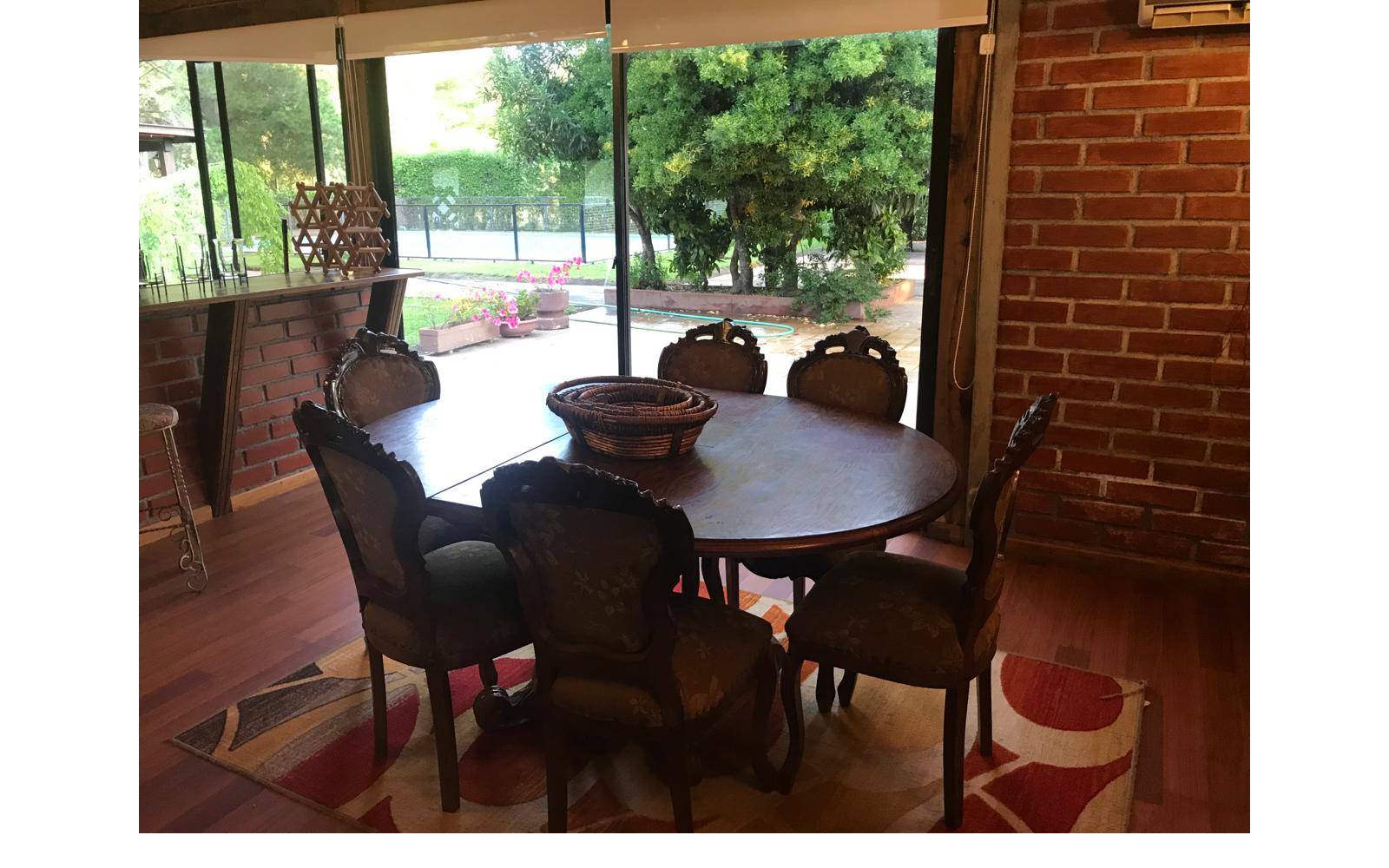 Comedor de madera con ventanal hacia el jardín exterior.