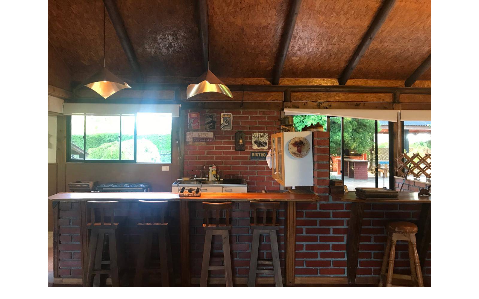 Barra de madera y taburetes integrada a la cocina rústica.
