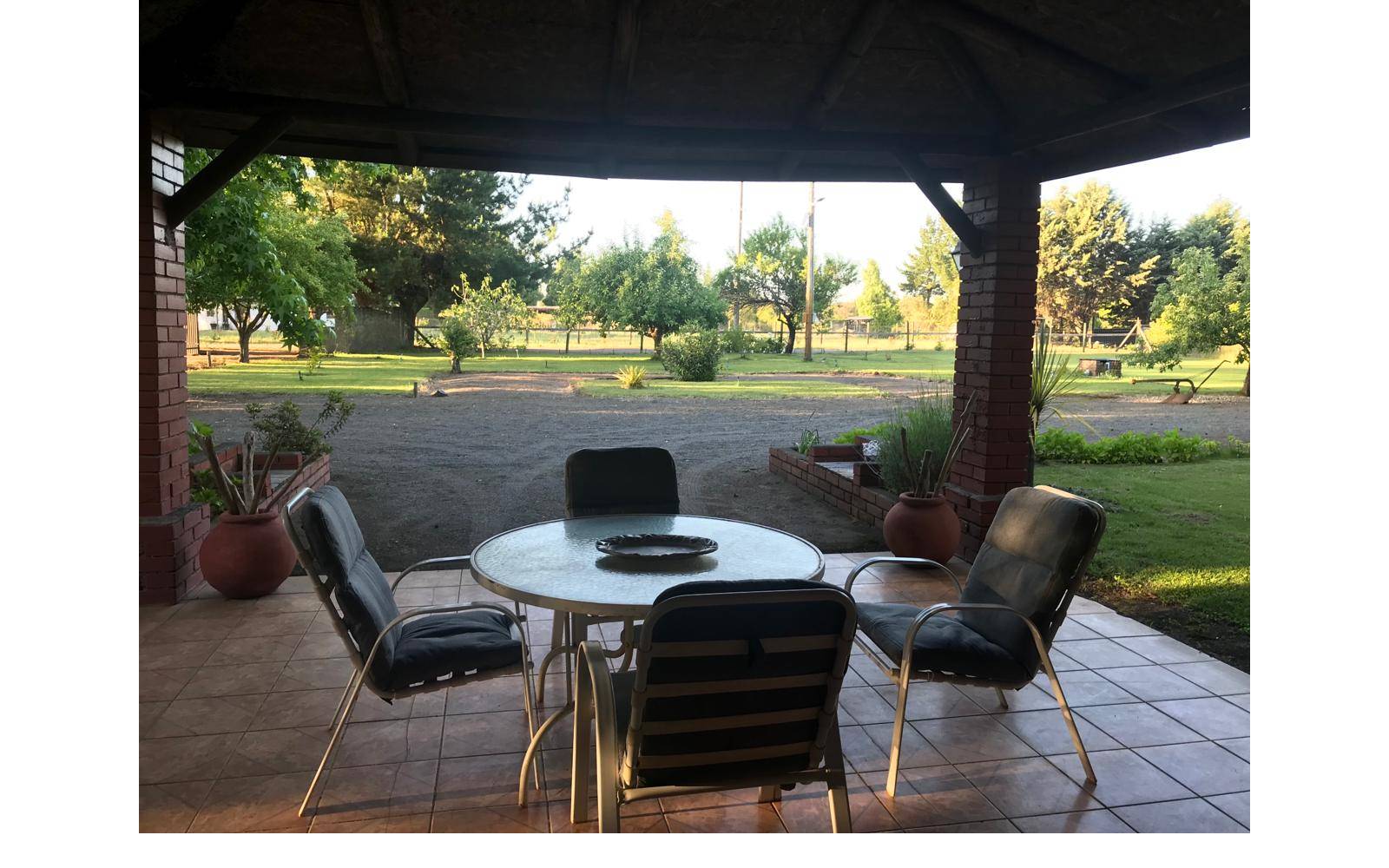 Terraza con juego de comedor exterior y vista al campo.