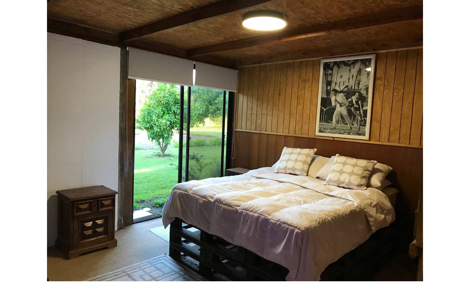 Dormitorio principal con cama doble y acceso al jardín.