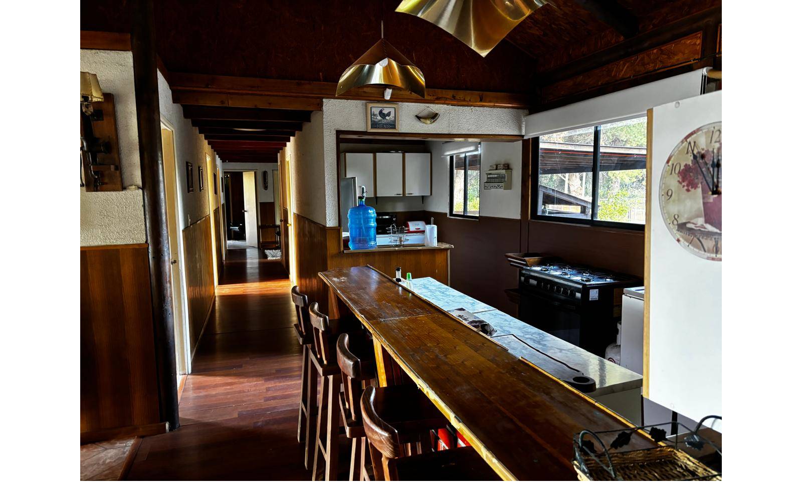 Barra americana de madera conectada a pasillo y cocina.