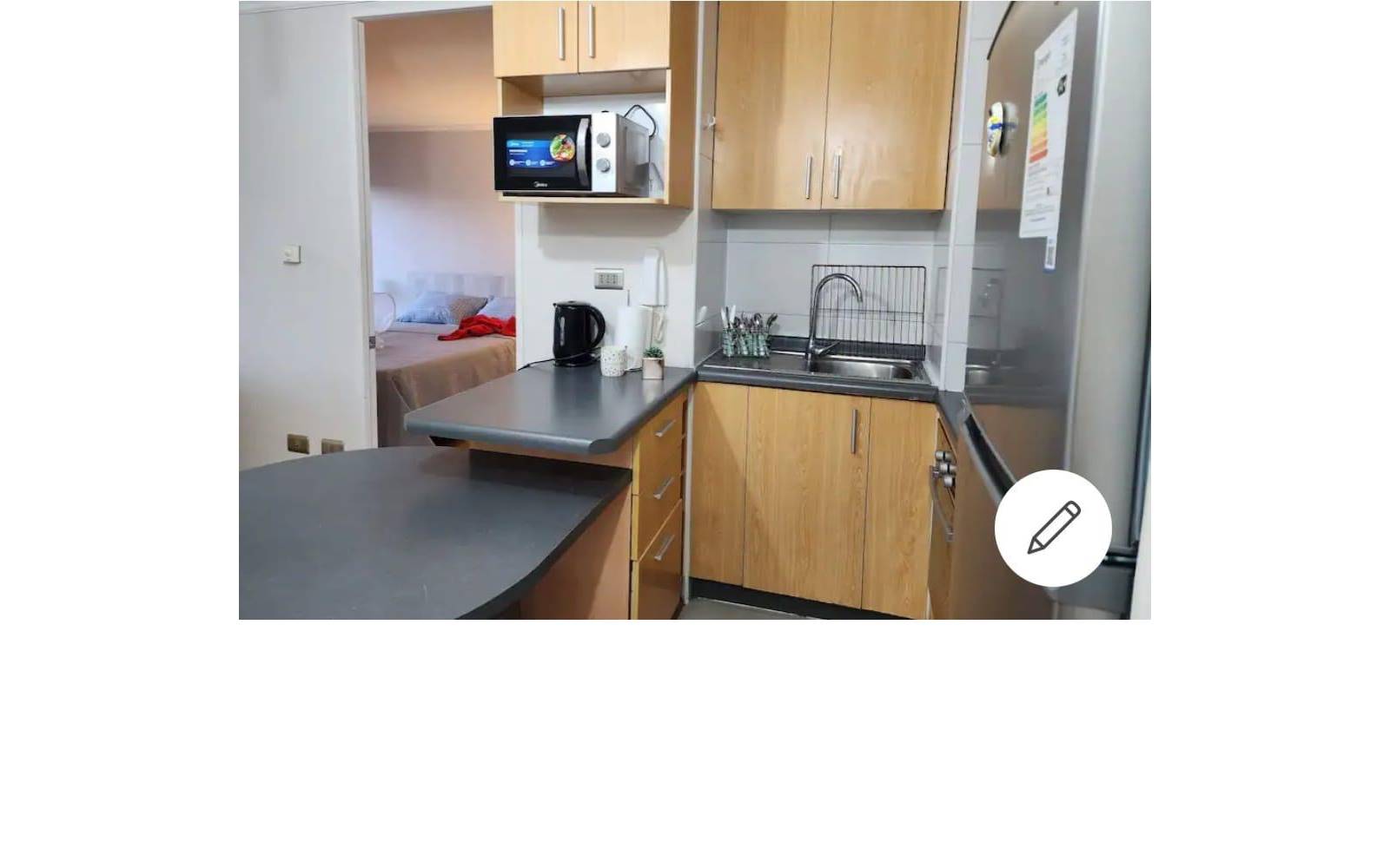 Cocina equipada con muebles de madera, encimera y microondas.